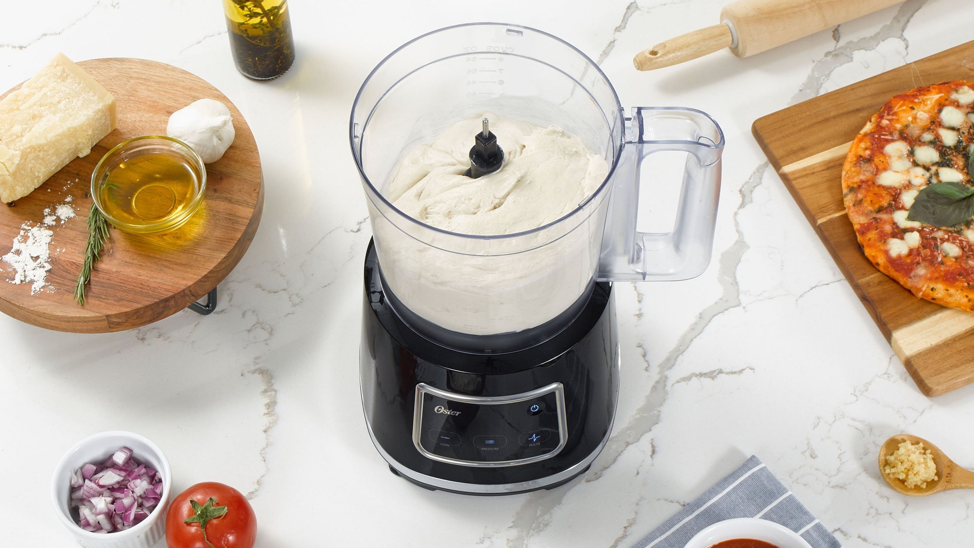 Le robot culinaire Oster de 10 tasses doté de la technologie Easy-Touch prépare de la pâte à pizza à partir de zéro, à côté des ingrédients