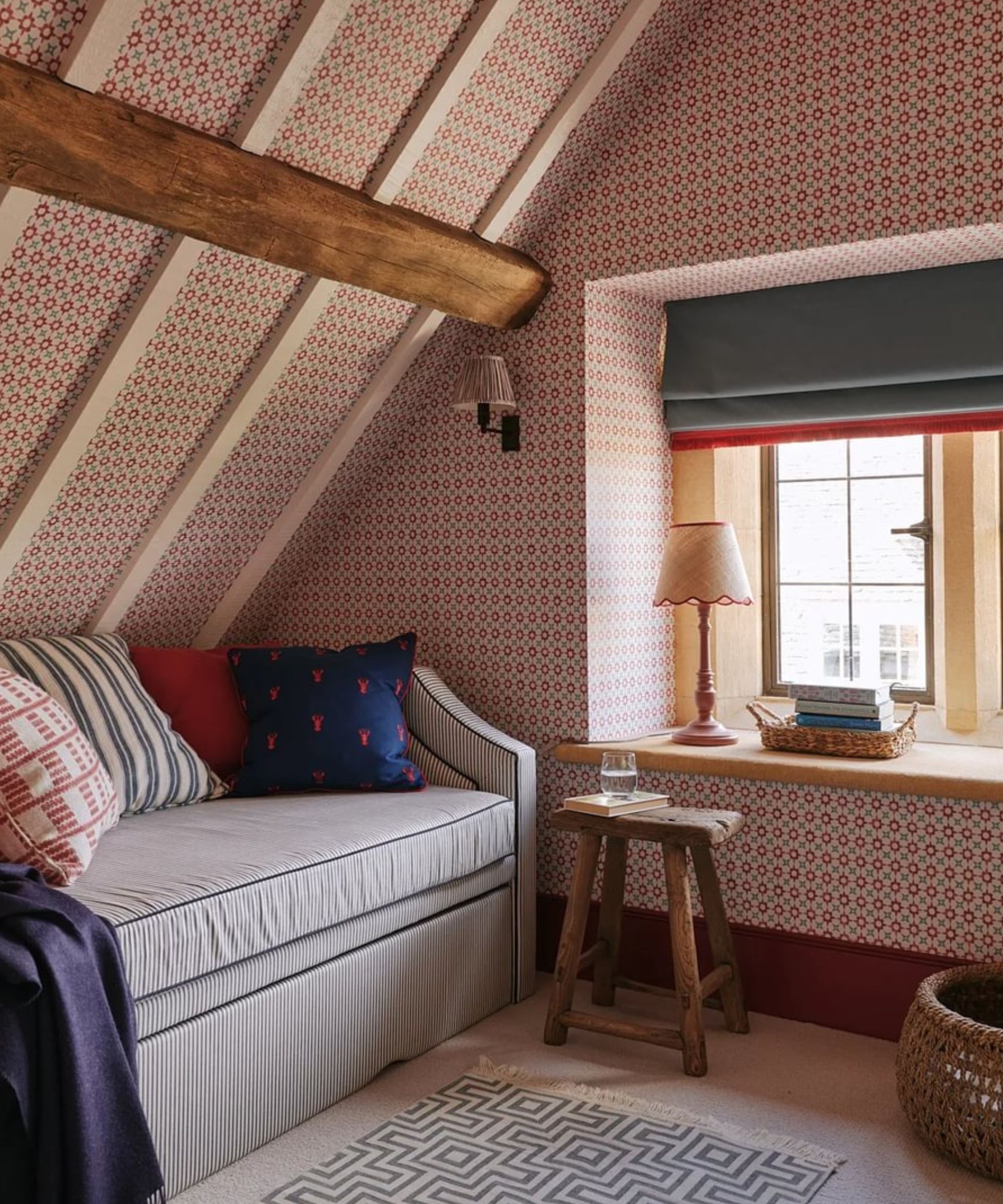 Chambre mansardée avec poutres, papier peint à petite échelle et canapé sous les combles