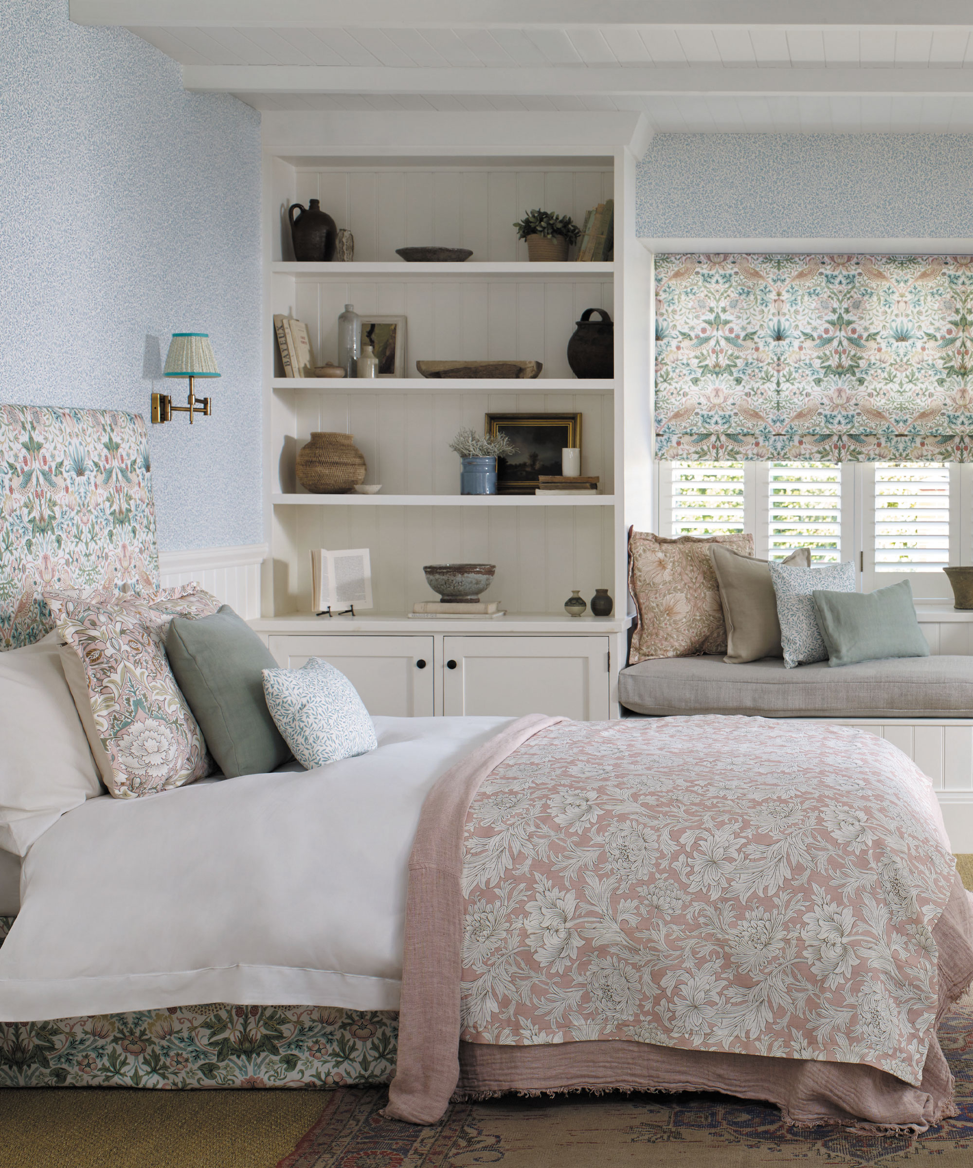 Chambre claire et lumineuse avec tissu assorti utilisé pour les stores et la tête de lit, grande étagère, banquette de fenêtre avec coussins dispersés