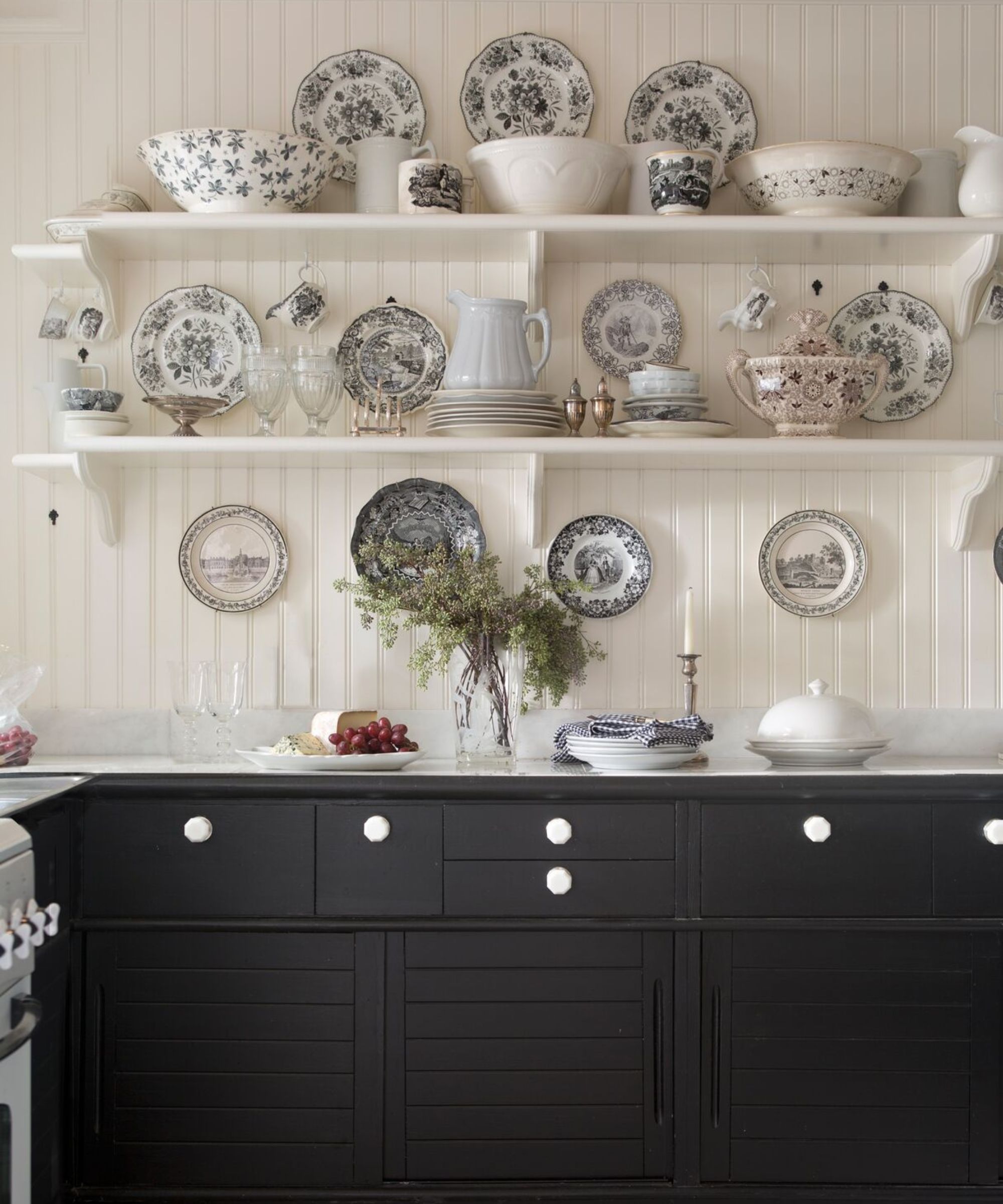 armoires de cuisine noires avec murs lambrissés en bois blanc, étagères au décor de ferme éclectique et vaisselle