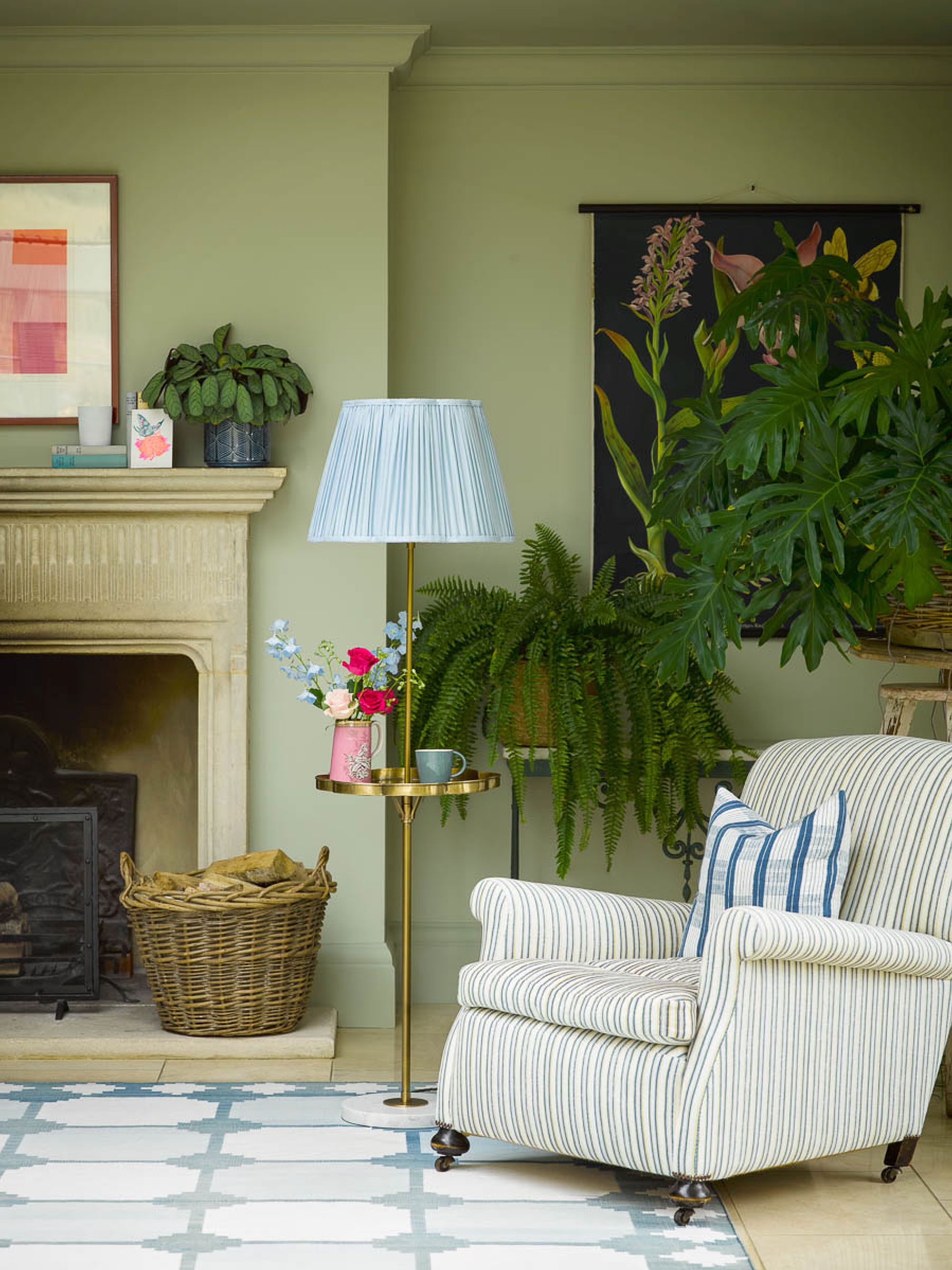 salon vert avec plafond peint, tapis bleu, fauteuil à rayures bleu, plantes, manteau, œuvres d'art, abat-jour bleu pâle sur lampe