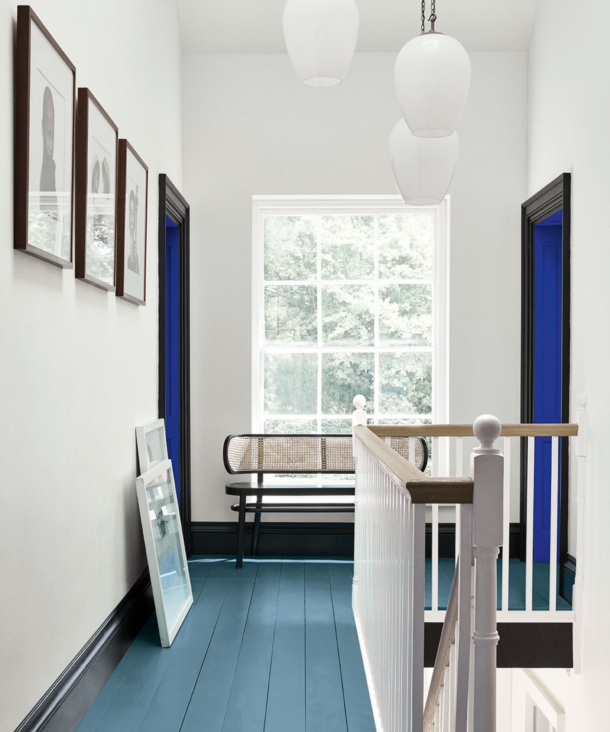 couloir avec murs blancs, grande fenêtre, plancher en bois bleu moyen, travail de garniture peinte en noir et bleu vif