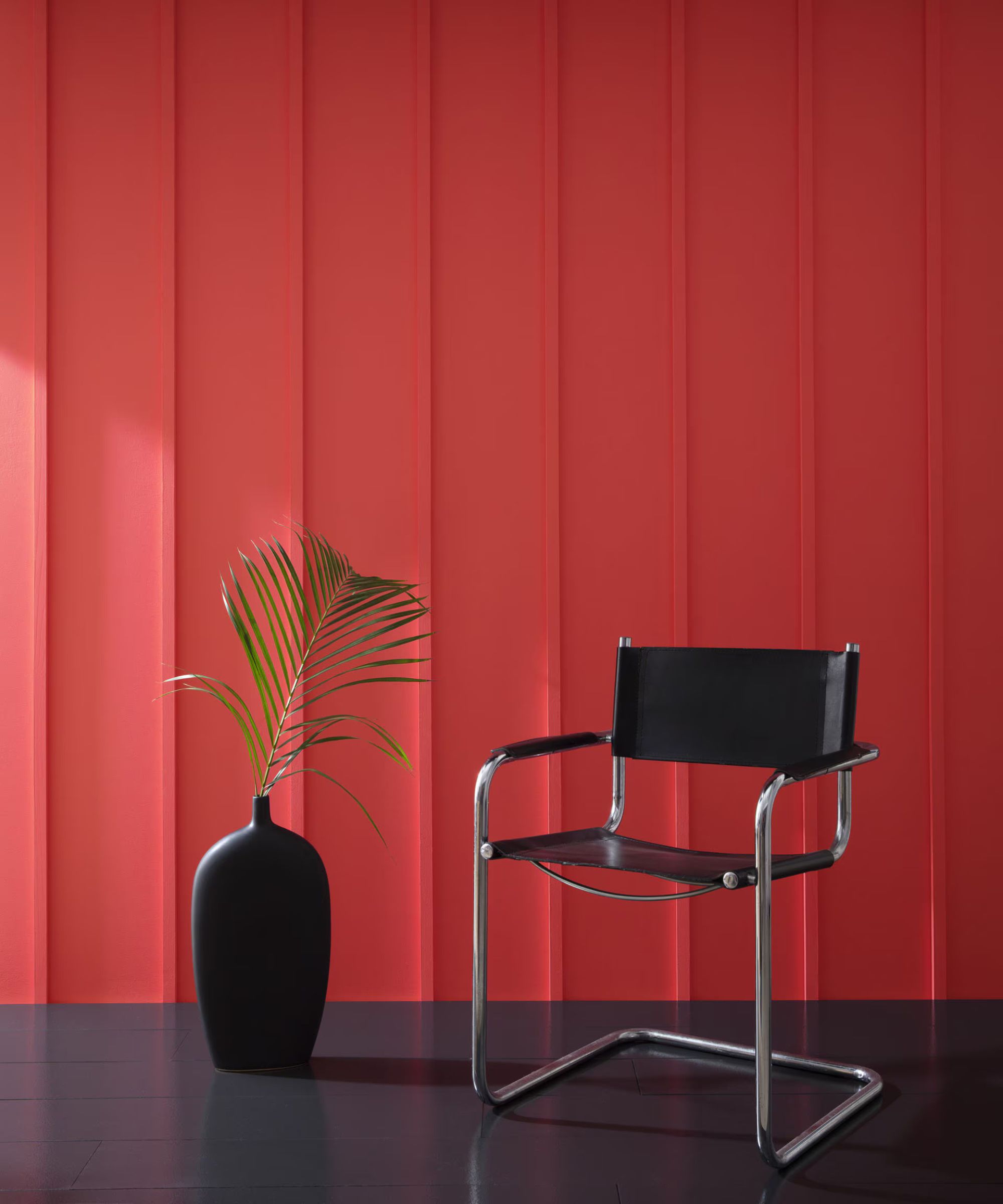 mur de lambris rouge avec chaise noire et vase noir avec feuille