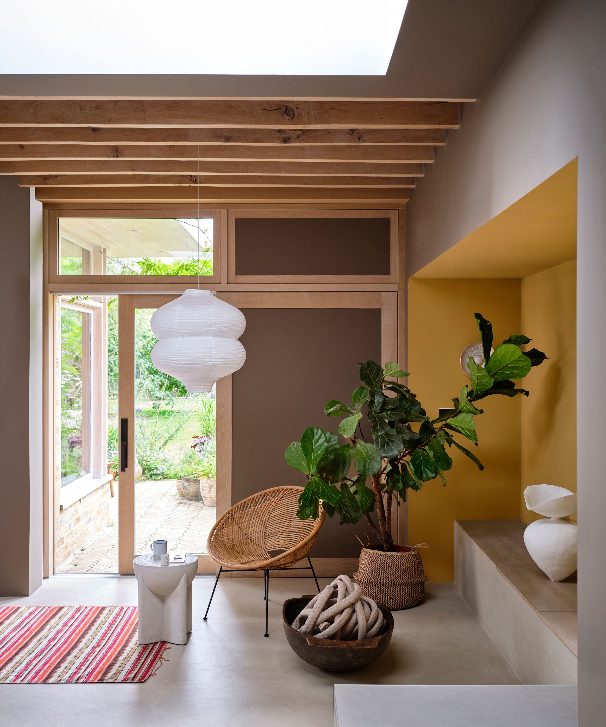 Espace de vie léger et ouvert avec mur d'accent jaune, mur brun, poutres de plafond en bois et décor boho