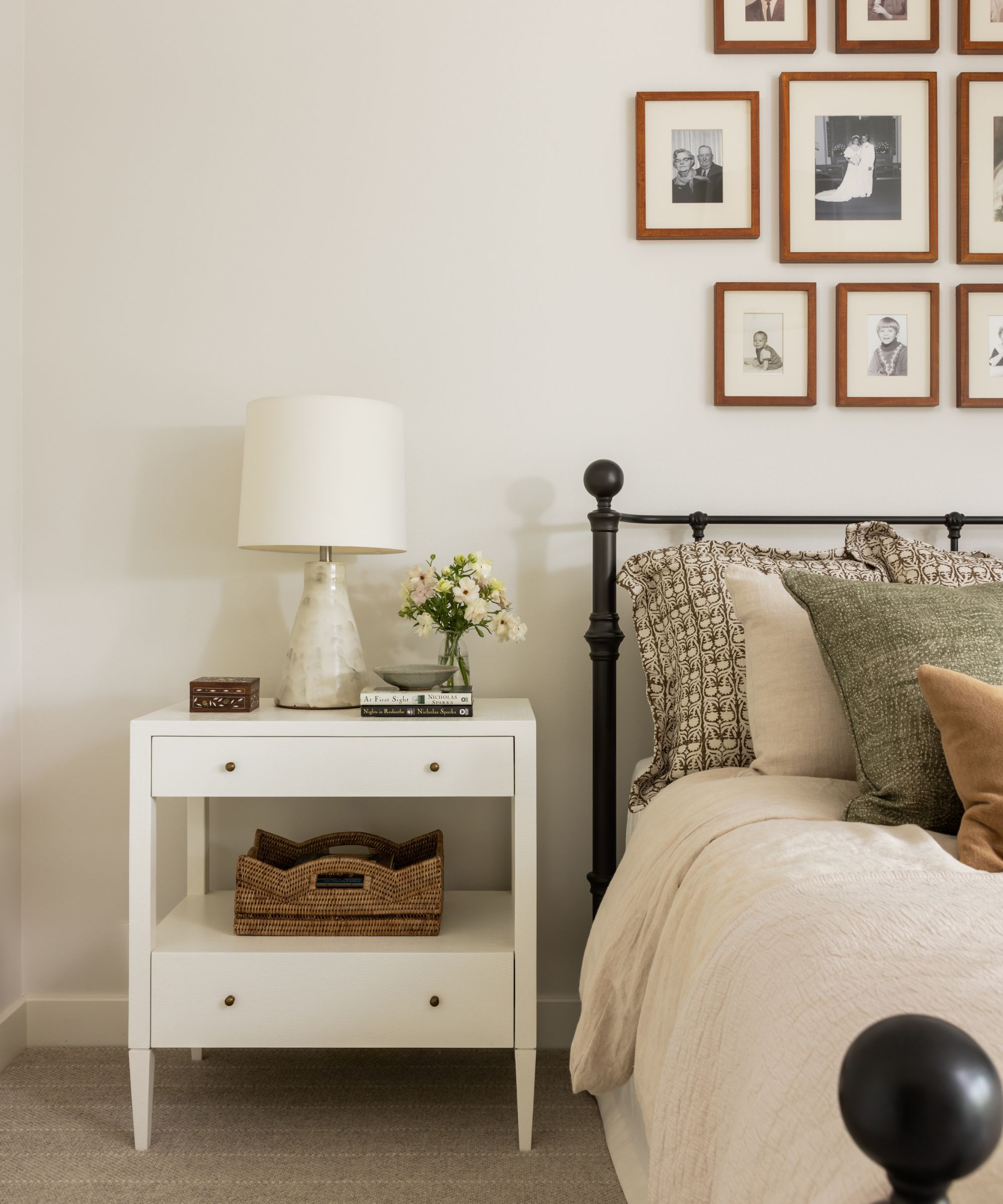 Chambre d'hôtes avec murs blancs, table de chevet blanc et lit de lit en métal noir avec mur de galerie au-dessus