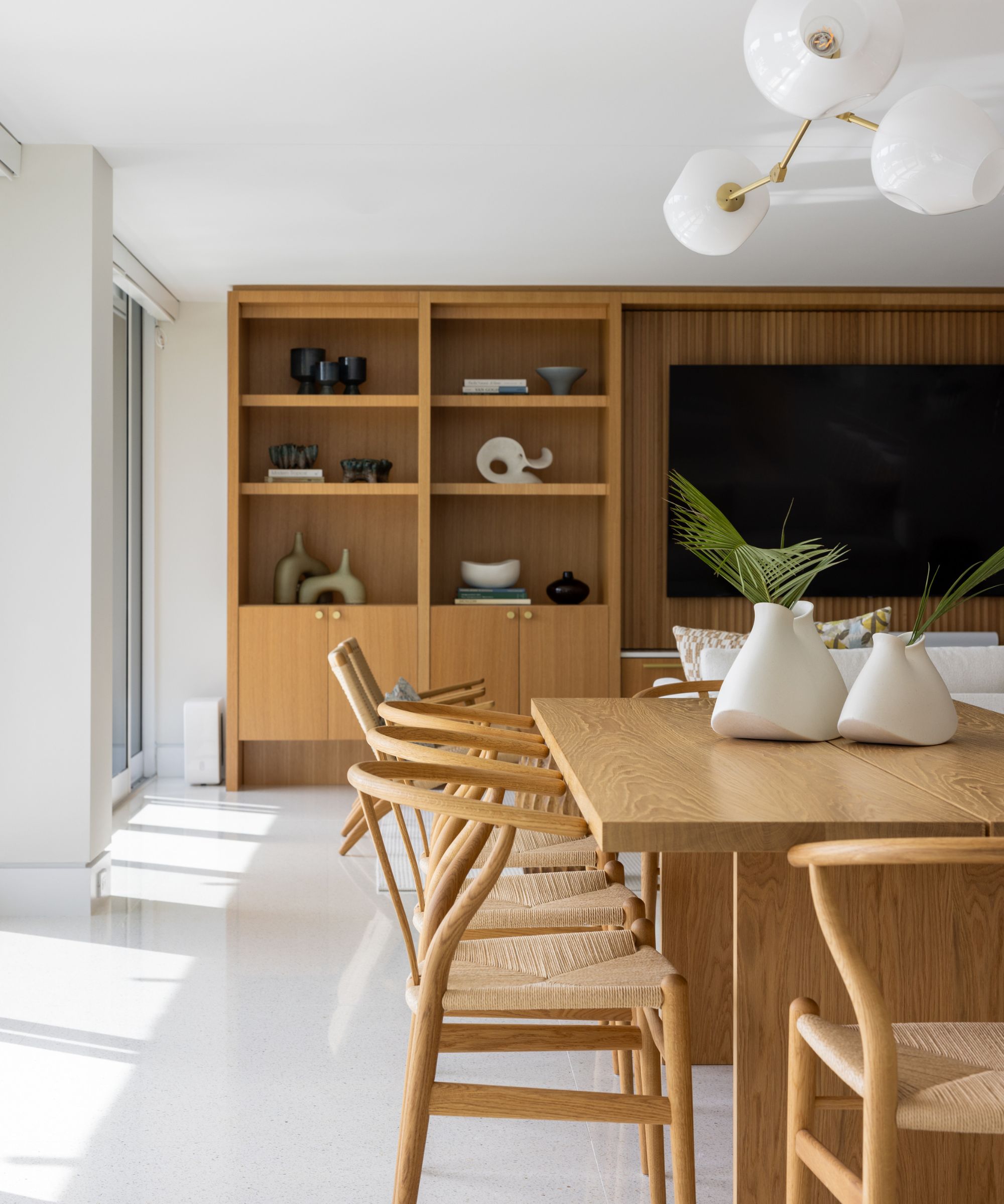 Espace de salle à manger en plein plan moderne Planchers et murs blancs blancs et mur de médias en bois avec table et chaises en bois et chaises