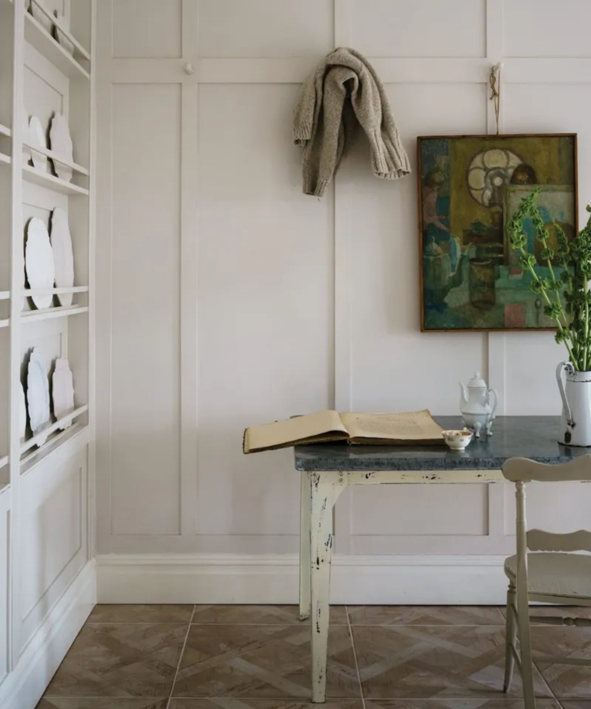 chambre avec des murs blancs, planchers de bois, bureau rustique et œuvres d'art sur le mur