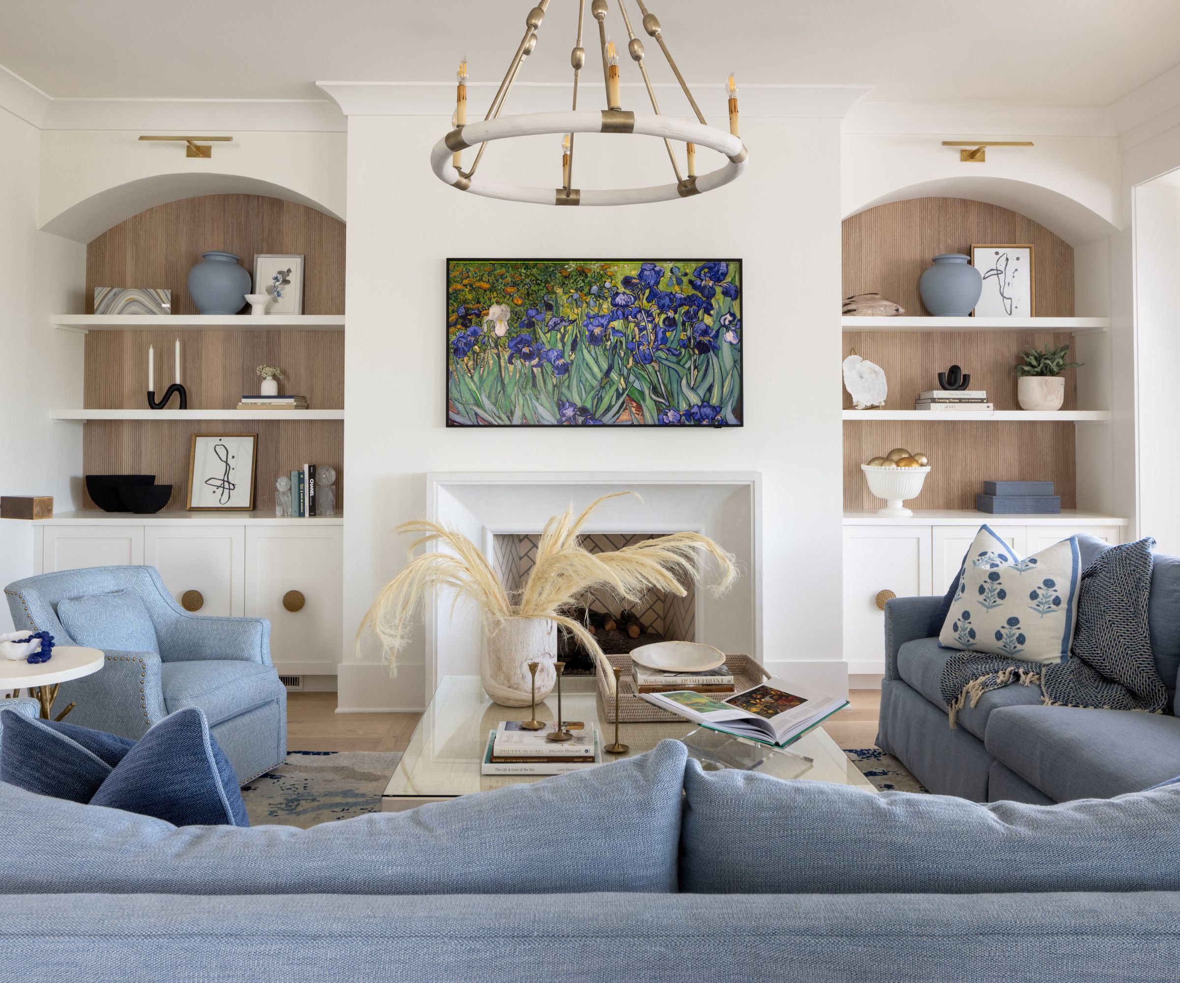 salon avec murs blancs, grand canapé d'angle bleu et fauteuil bleu, alcôves arquées avec étagères