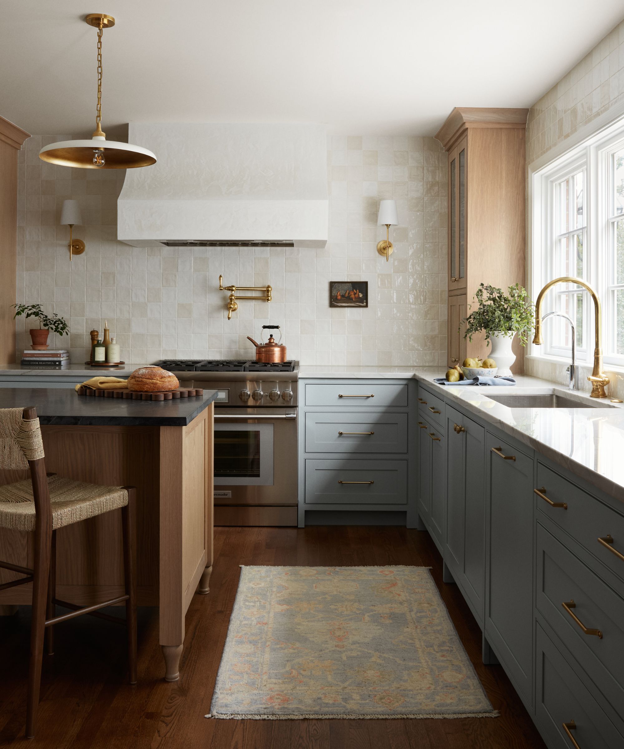 Une cuisine en bois et bleue avec une cuisinière chromée et un matériel en laiton brossé
