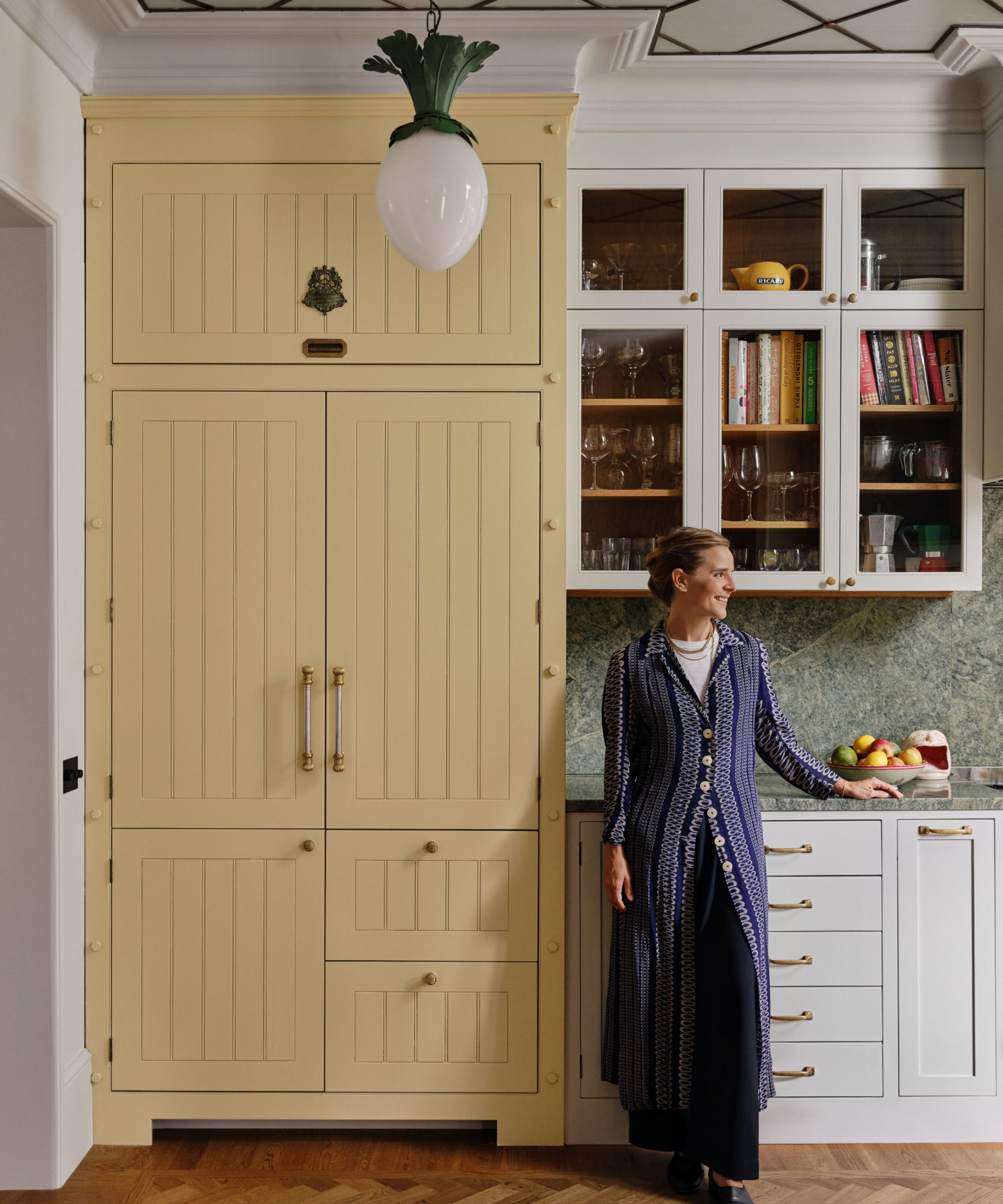 Beata Heuman x Mylands Paint Collaboration Portrait de designer se tenait dans sa propre cuisine avec une grande armoire de réfrigérateur jaune au beurre