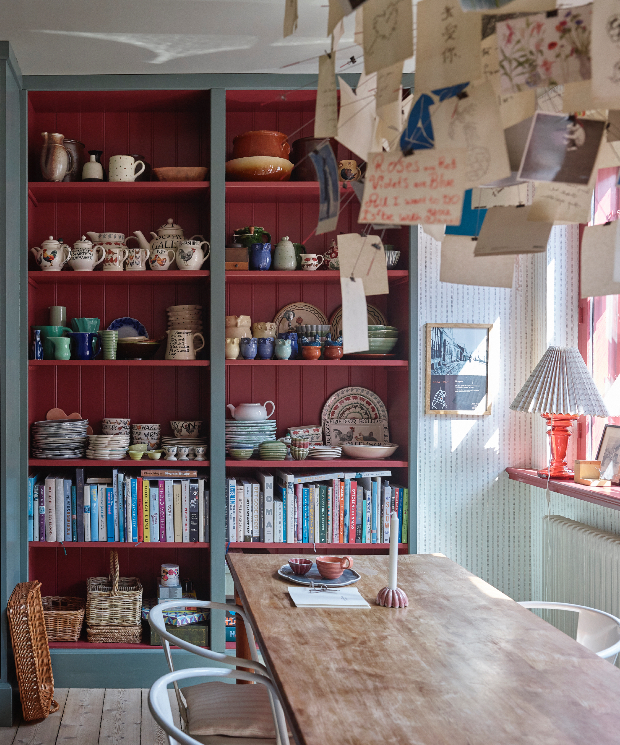 Espace à manger de cuisine avec étagères ouvertes avec intérieur rouges, livres et vaisselle, table à manger, Farrow & Ball: Asger Mortensen, Wester Agency
