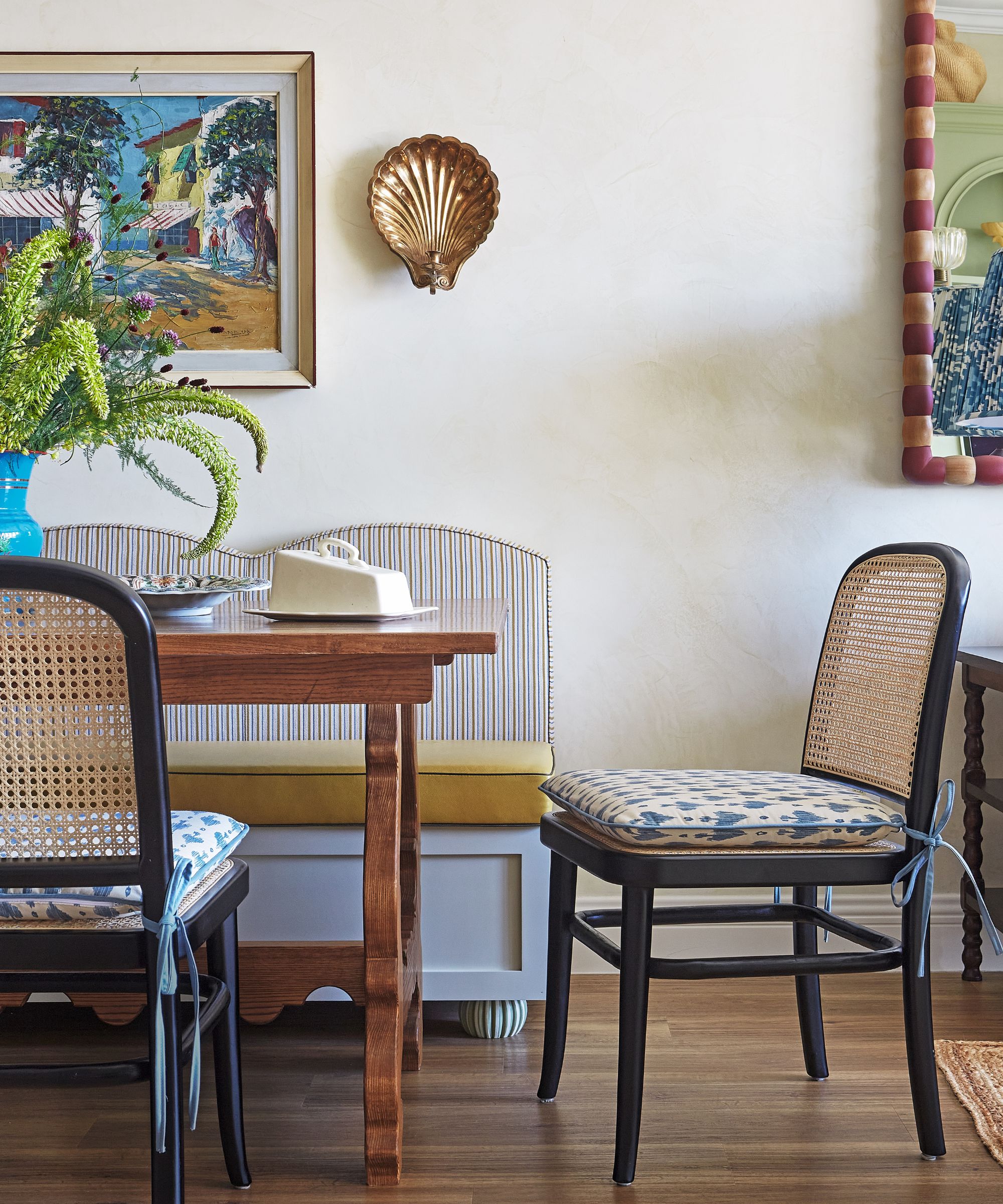table à manger avec coussins à motifs et banc et œuvres d'art derrière
