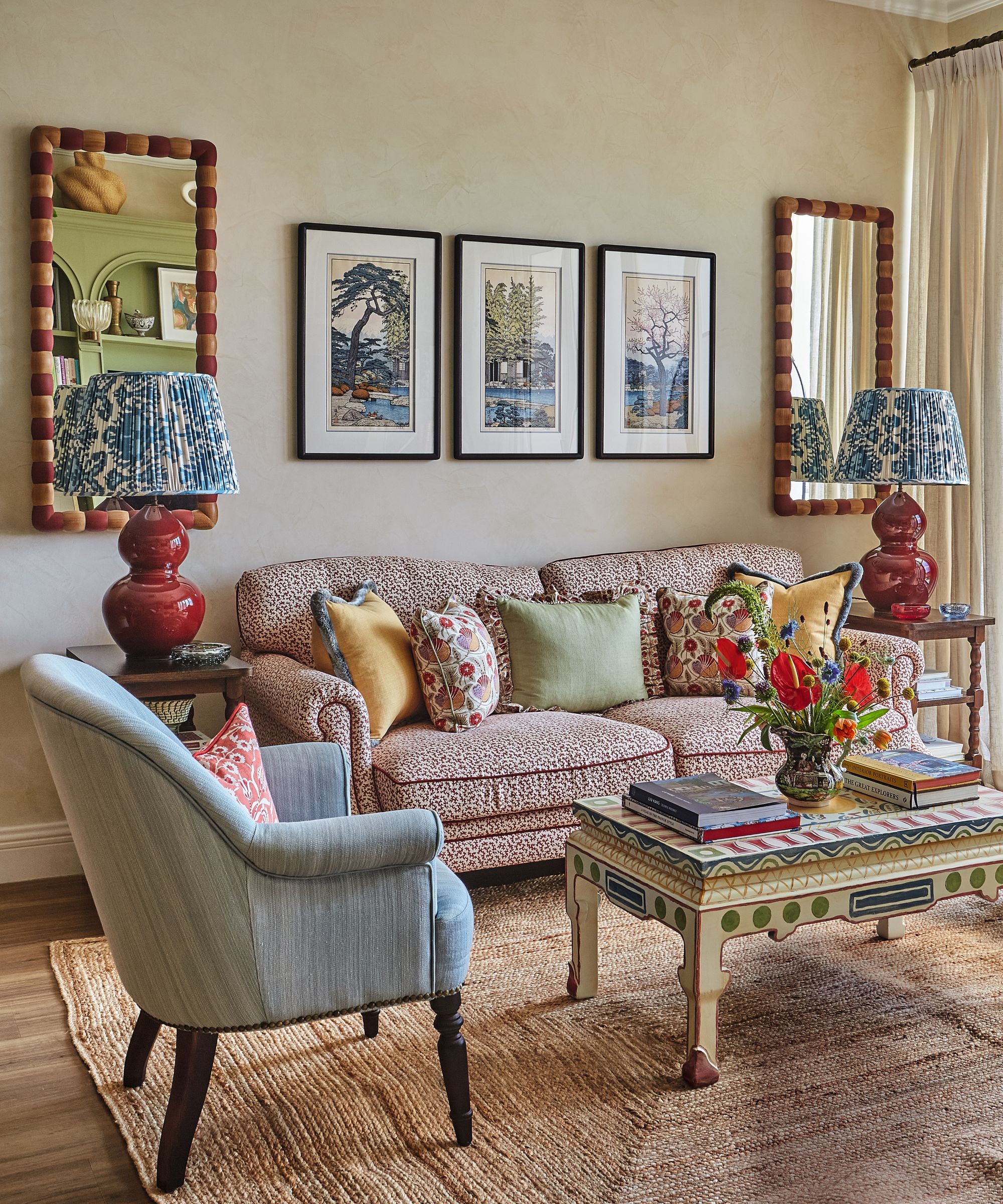 Salon avec canapé à motifs et fauteuil et herbe marin texturé et Colourgul Table de café en bois peint sur les murs avec des miroirs symétriques