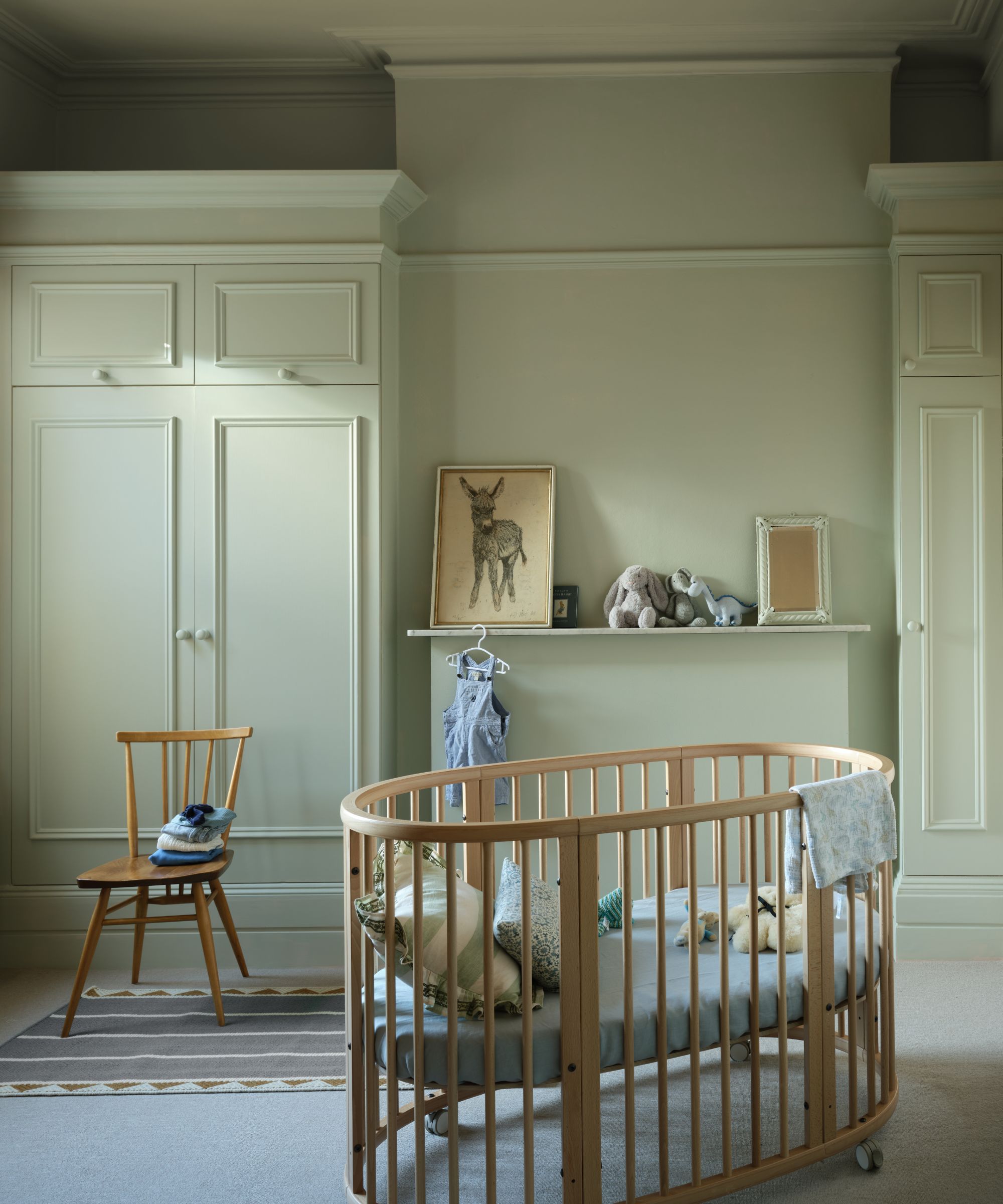 Salle de pépinière avec des murs verts pâles, un lit en bois et une chaise