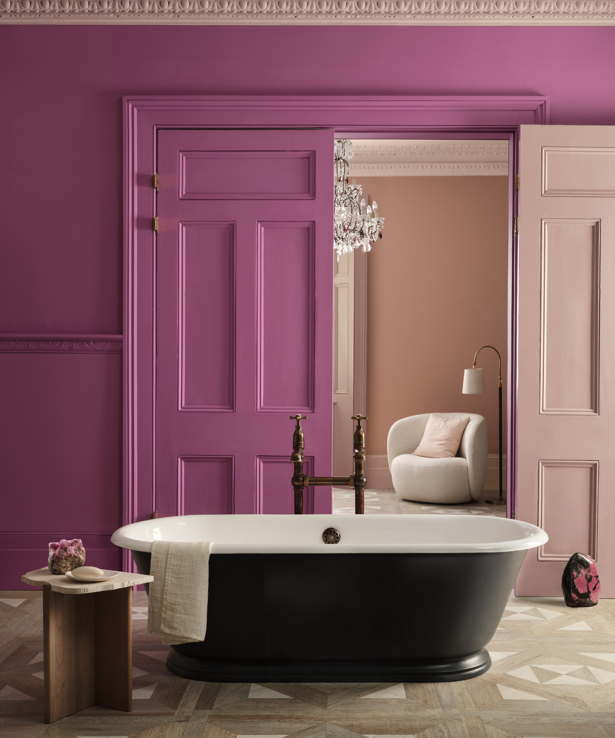 Salle de bain magenta avec baignoire en haut noir, vue rose pâle à l'intérieur de la chambre avec porte assortie, table d'appoint, plancher en parquet