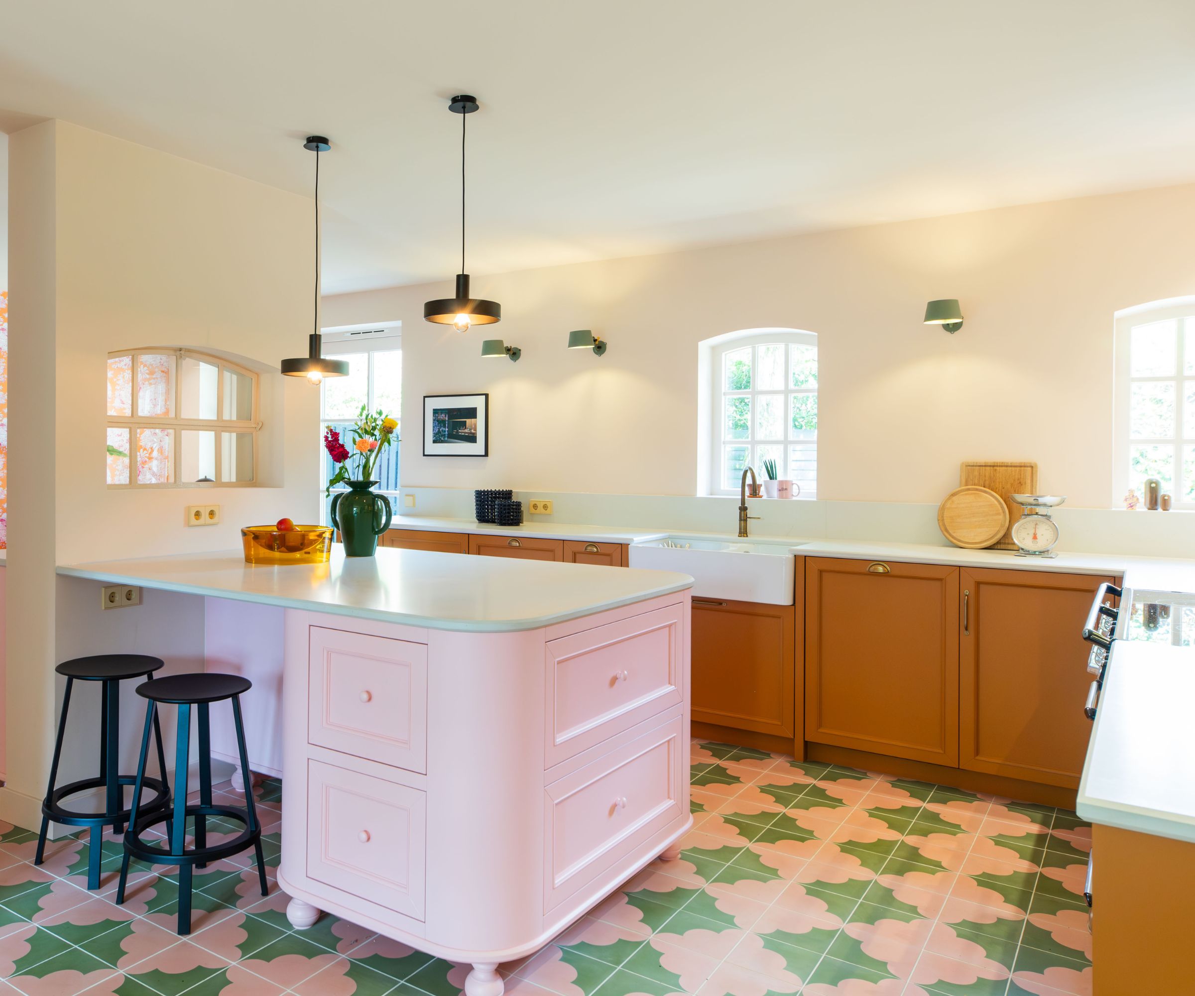 Une cuisine rose, verte et jaune avec des carreaux de sol à motifs