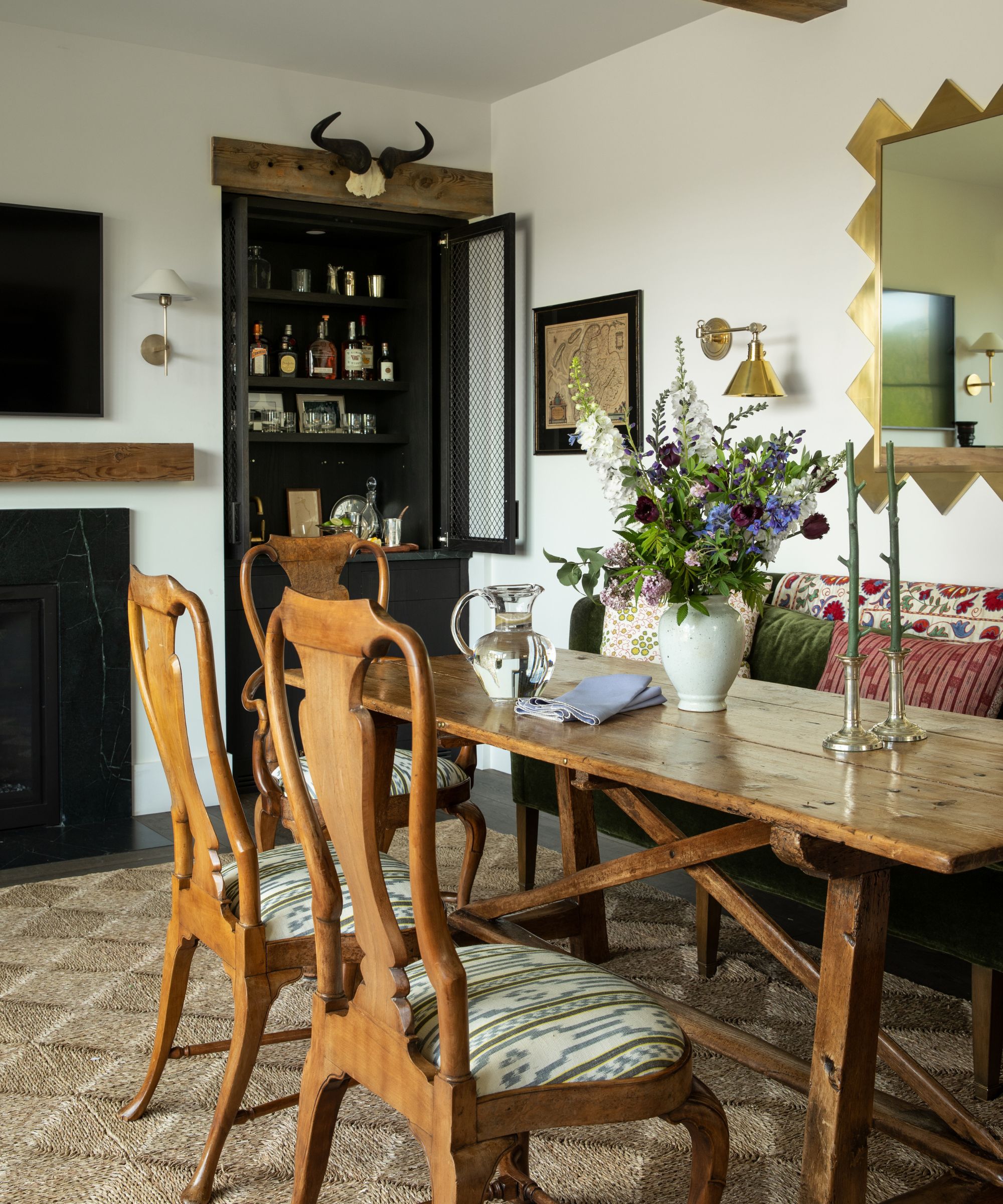 Salle à manger rustique avec chaises et table en bois, canapé en tissu, armoire à fleurs et boissons florales