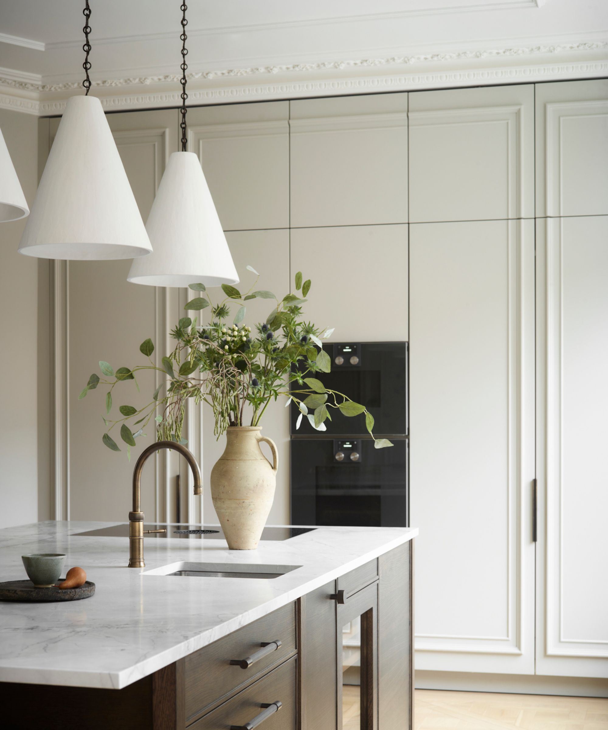 Cuisine avec armoires de couleur pâle et île en bois foncé avec dessus en marbre gris