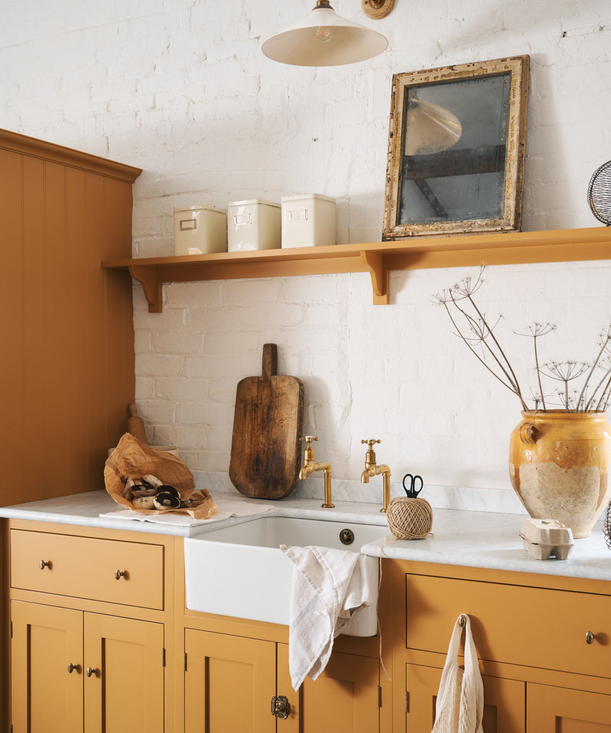 coin de cuisine avec armoires jaune foncé, mur de briques blanc et décor rustique