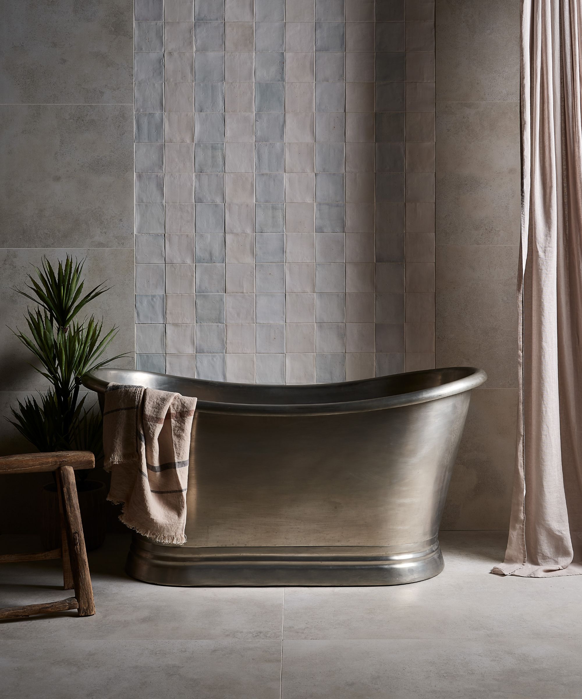 Mur de carreaux rayés avec gris et bleu, sol de salle de bain en marbre et grande baignoire en métal