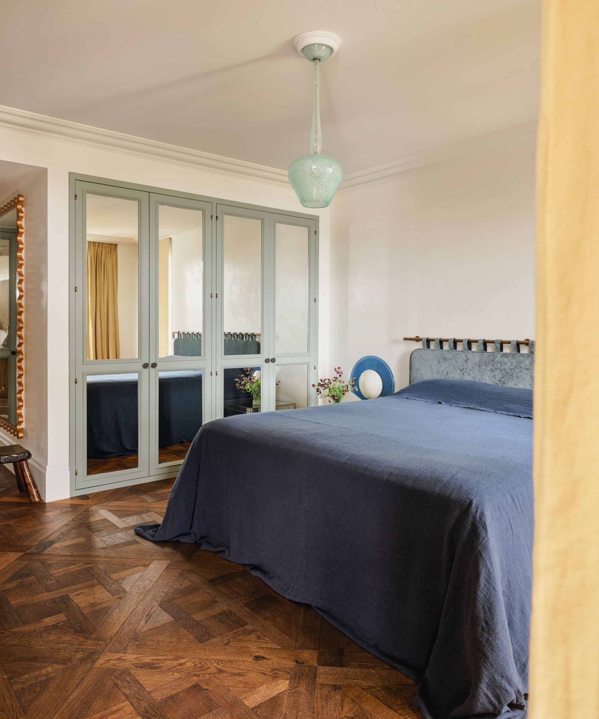 Chambre à coucher avec literie bleue et parquet en bois et pendentif en verre bleu clair