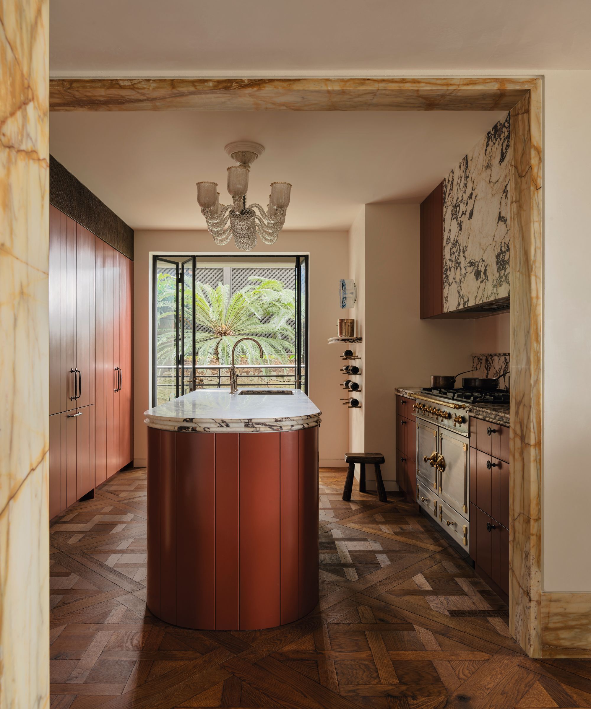 Cuisine avec plancher en bois et îlot de cuisine courbe de couleur rouille et détails en marbre