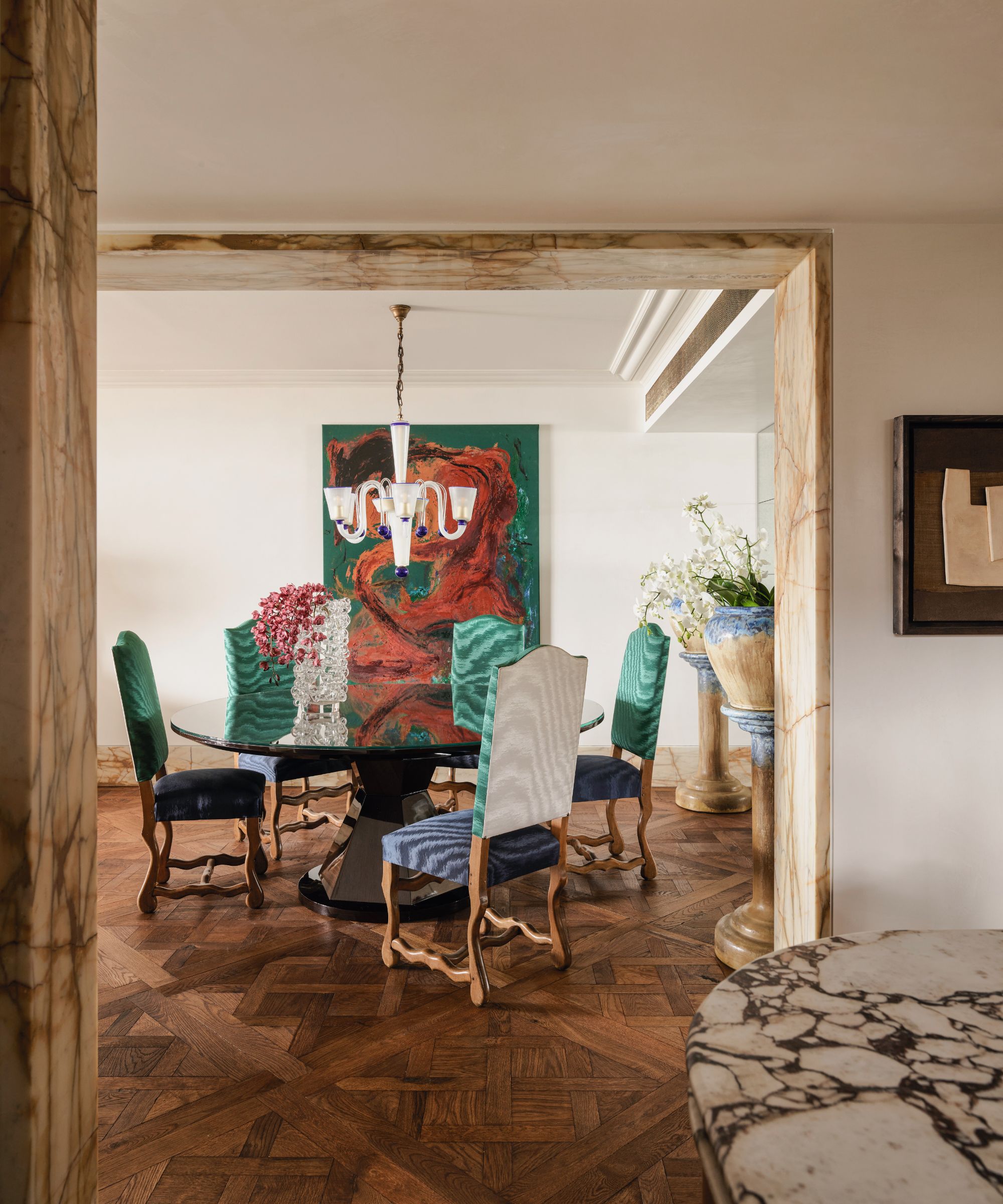 Salle à manger avec planches à motifs en bois et chaises rembourrées colorées et illustres abstraites colorées