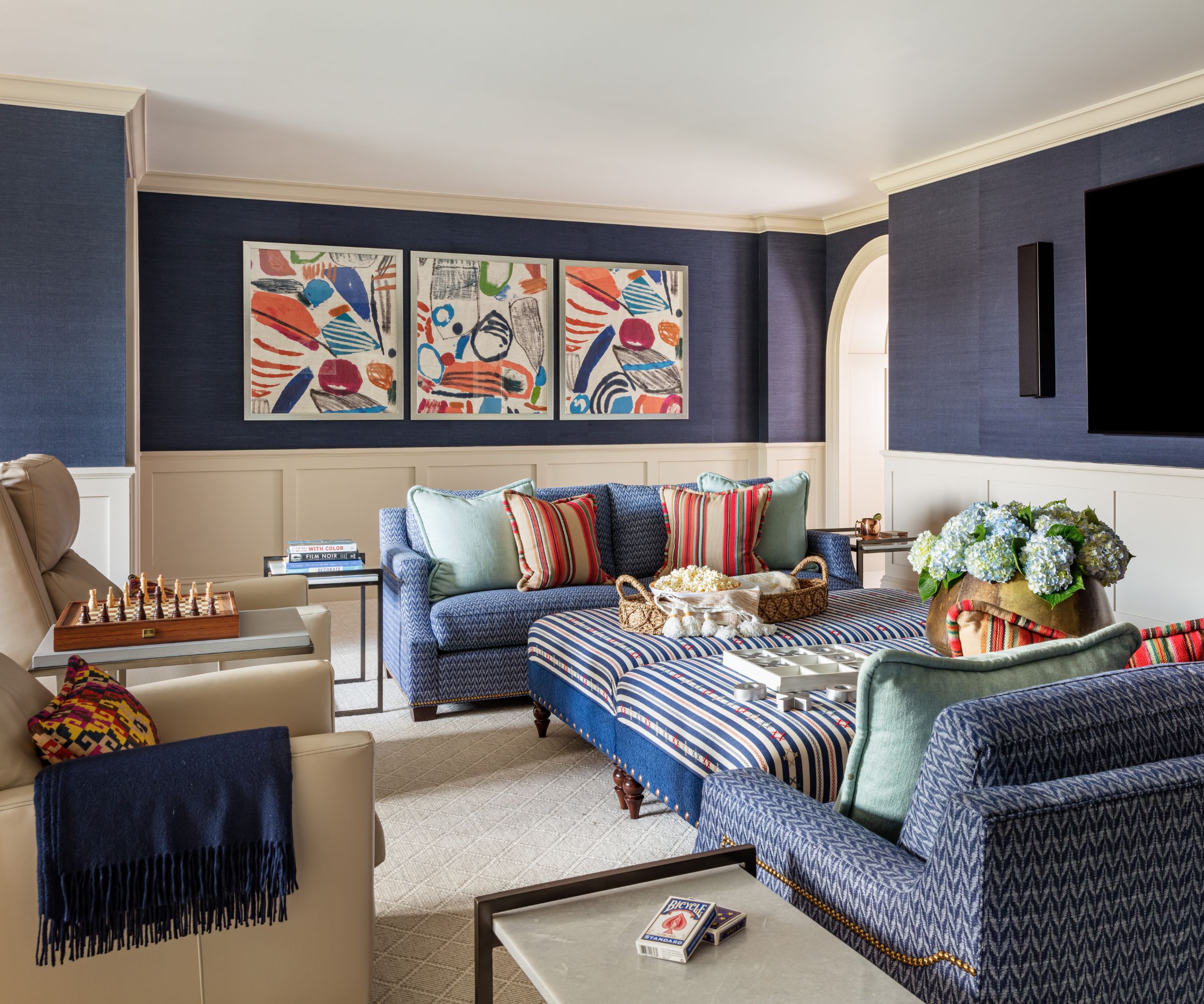 Espace de vie confortable avec des murs bleu foncé et crème, des canapés bleus, des coussins colorés et des œuvres d'art