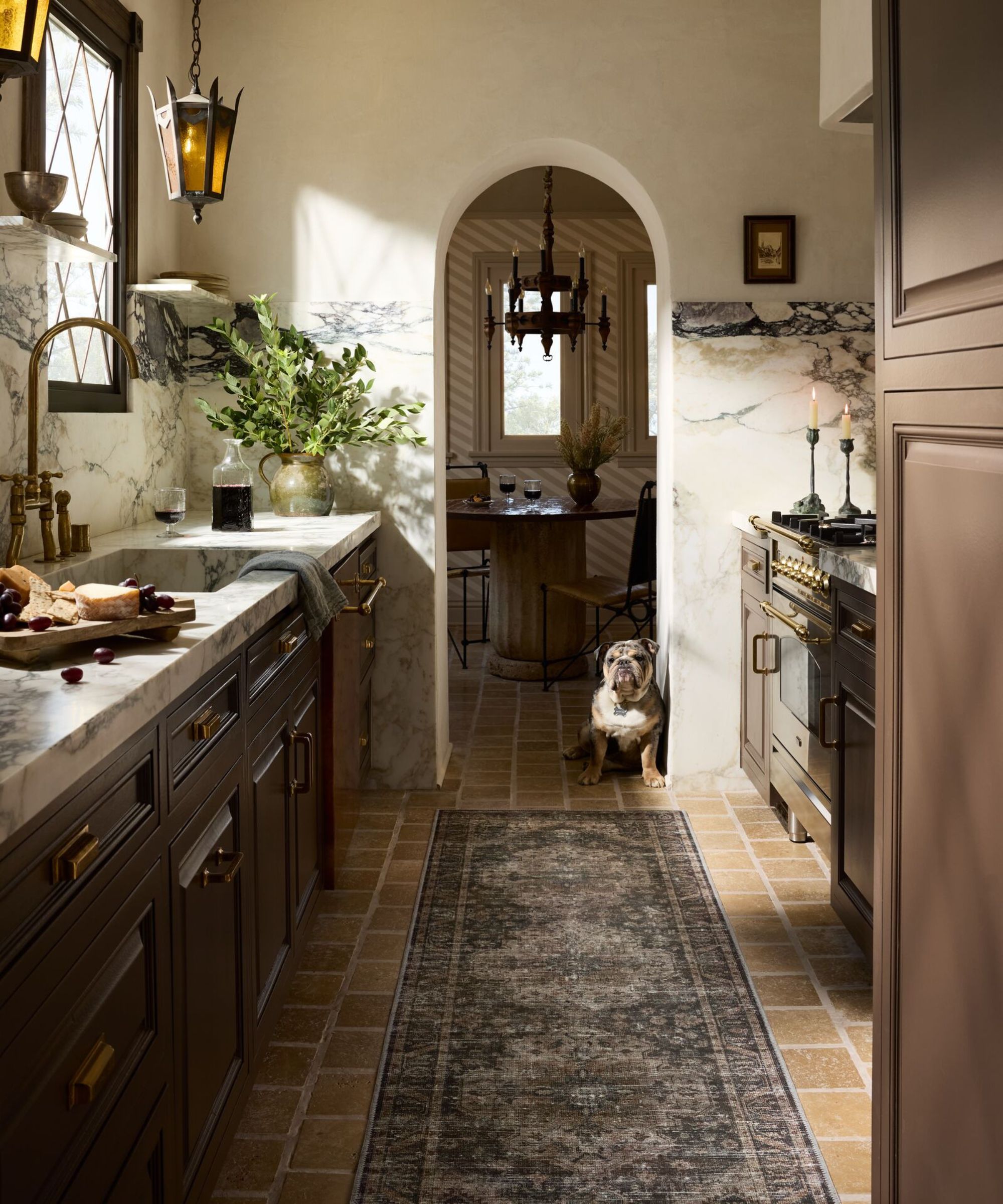 Cuisine regardant vers le coin du petit-déjeuner avec porte voûtée, boiseries en marbre, lumière de pendentif antique