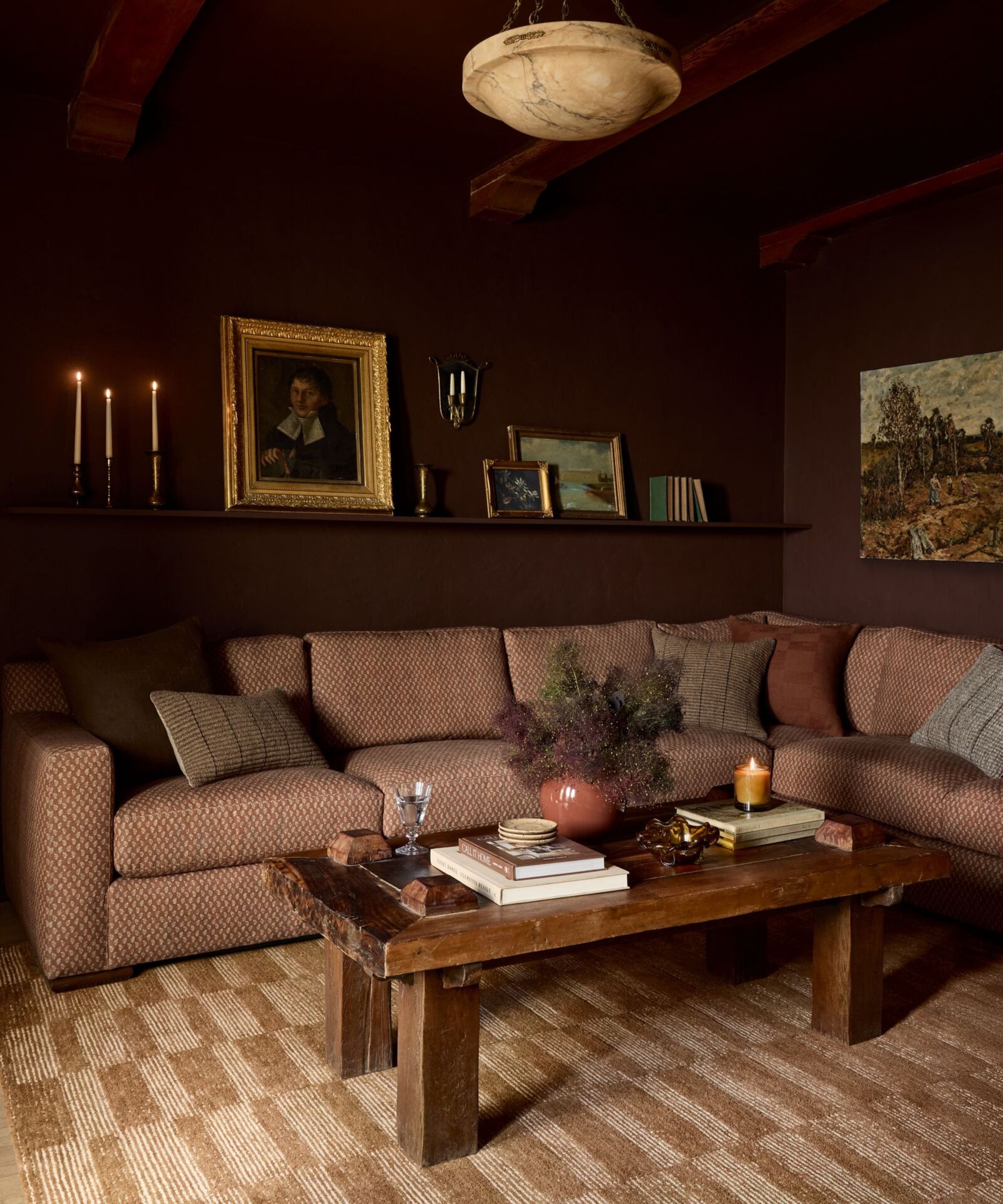 Salon de Bourgogne foncé avec des peintures antiques, un canapé en lin, une table basse en bois et un tapis à carreaux