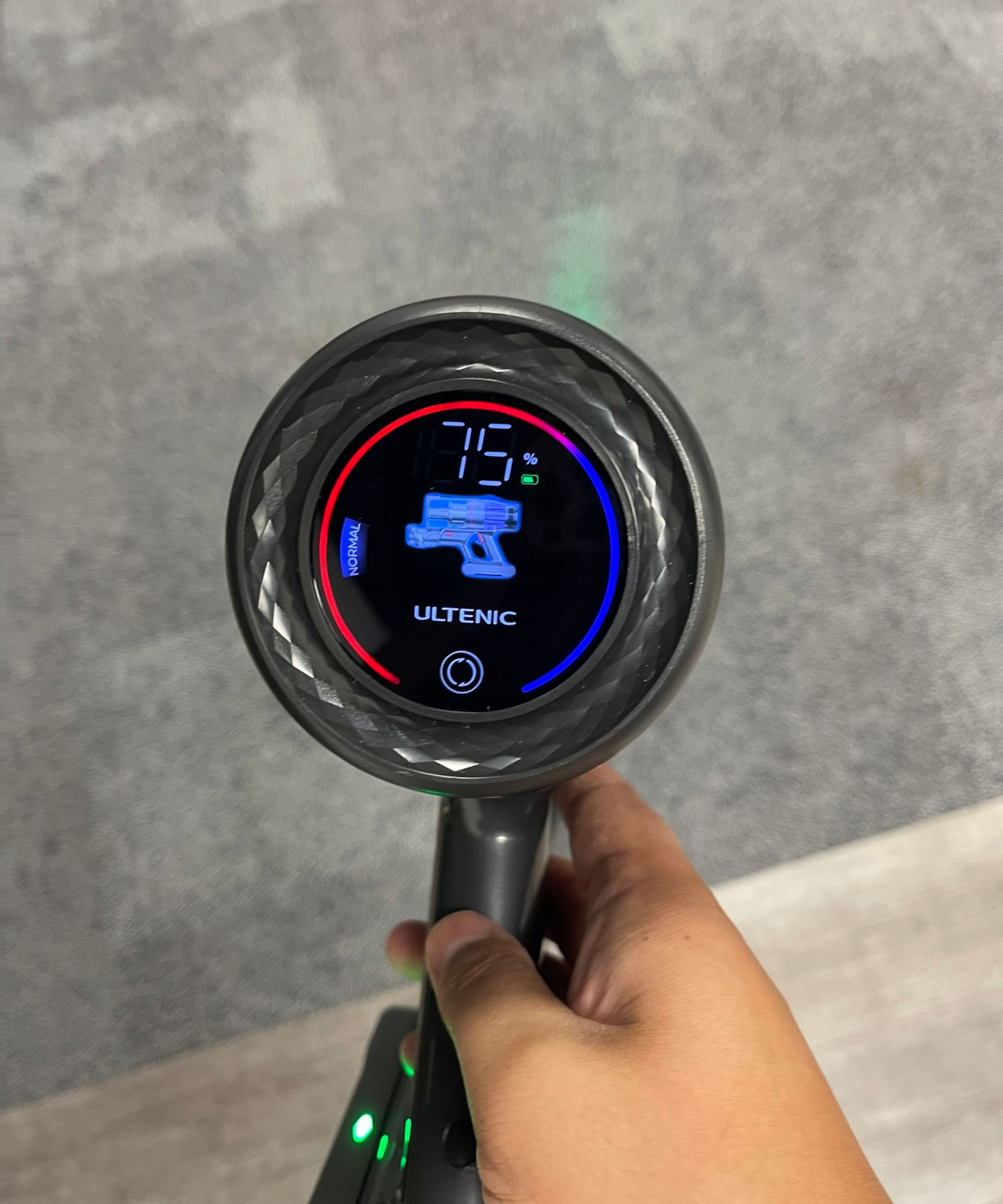Gros plan de l'écran de contrôle tactile de l'Ultenic U16 Flex, tenu entre Dan dans le centre d'essai du futur contre le tapis gris.