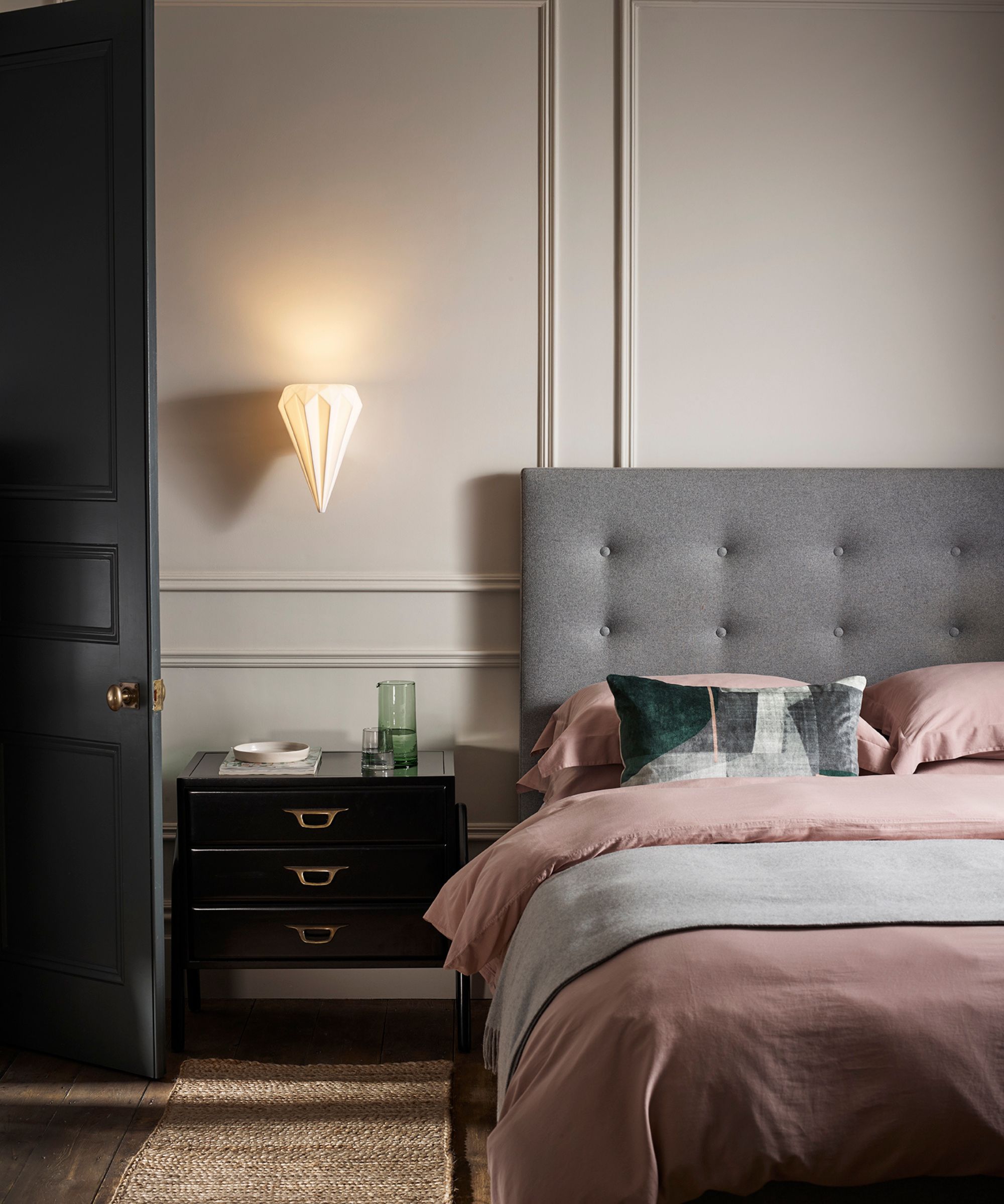 chambre à coucher avec tête de lit grise, literie rose et navette noire