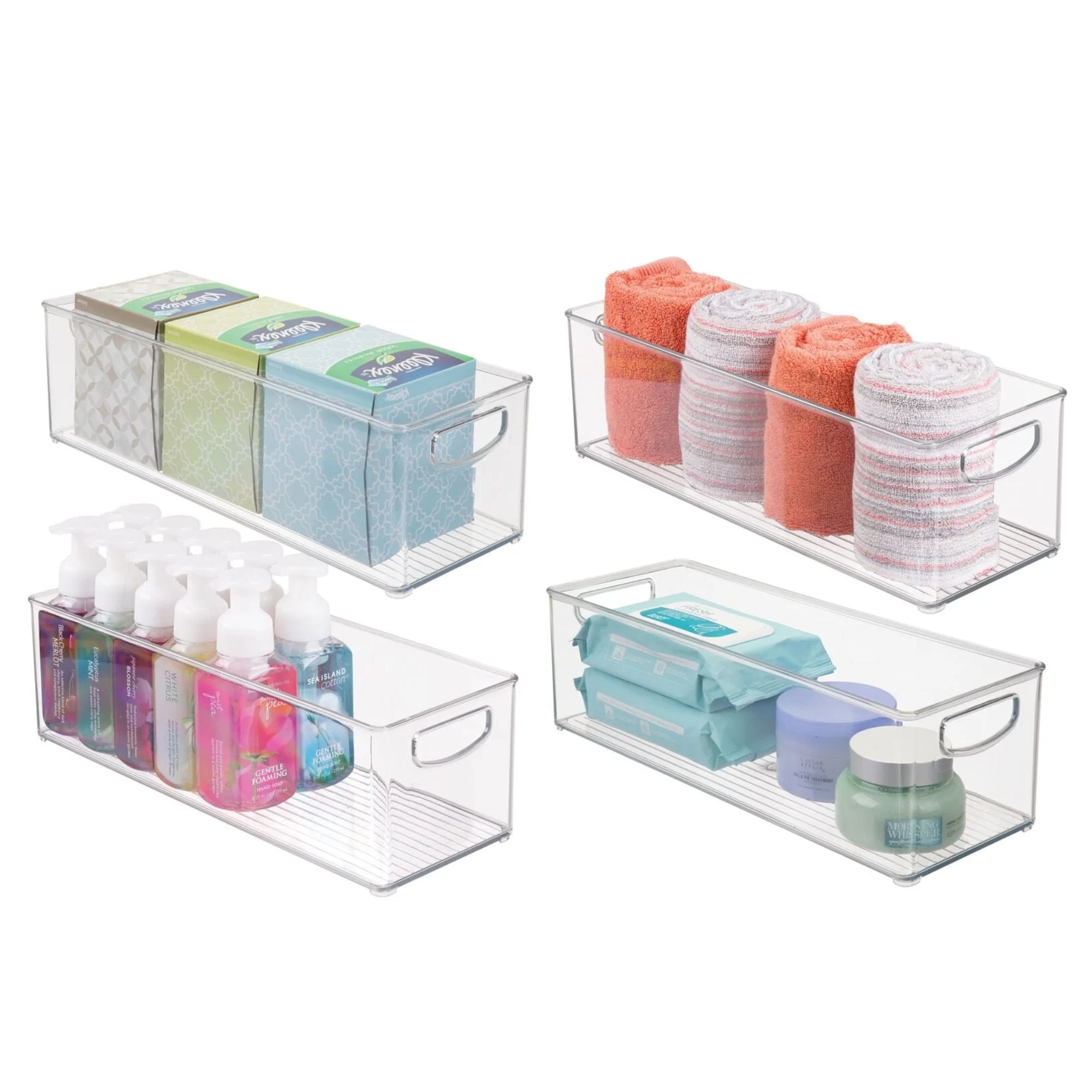 Quatre bacs de rangement en plastique transparent avec des poignées intégrées et une base striée remplie de tissus verts, bleus et blancs, des serviettes orange et rayées, des bouteilles de soap avec les couvercles blancs et diverses articles de toilette