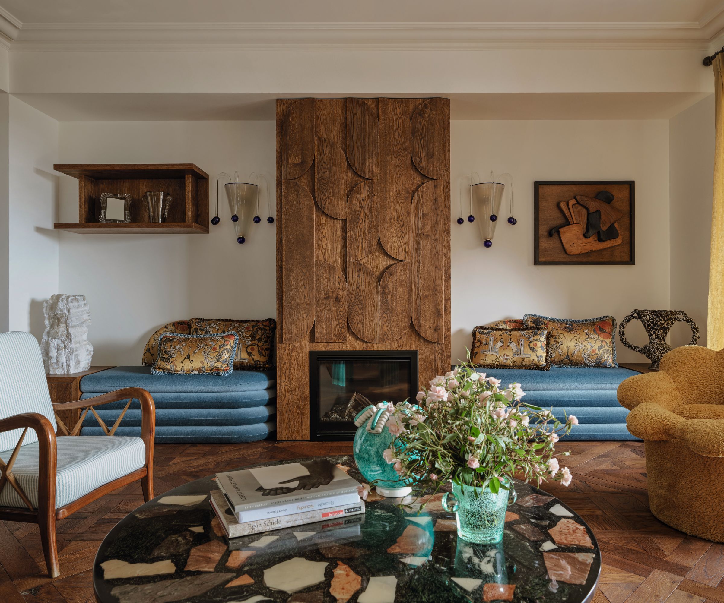 salon de vie avec planches en bois et sièges en velours bleu intégré et table basse en marbre en terrazzo