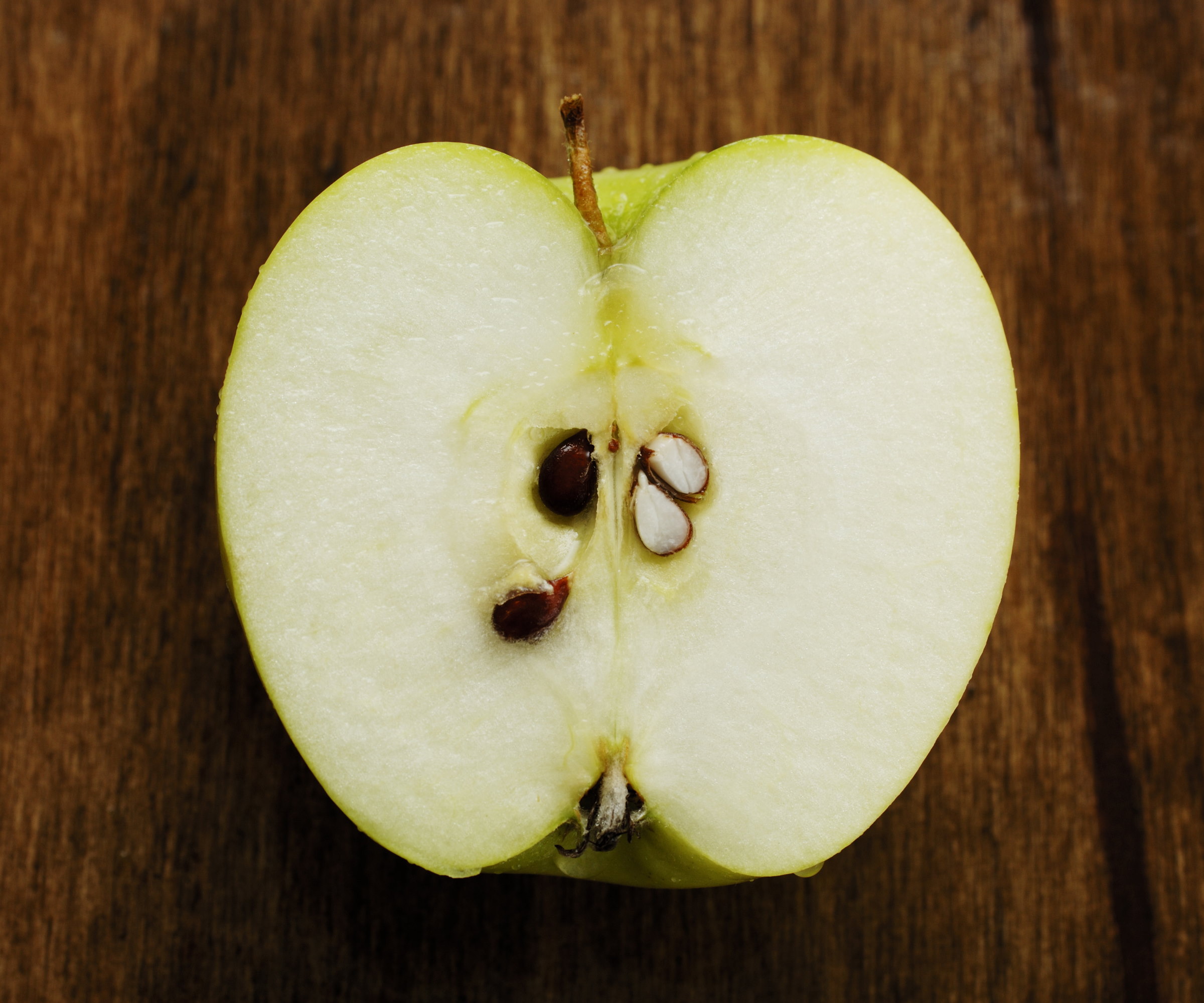 Une pomme coupée en deux sur une planche en bois pour montrer les graines à l'intérieur