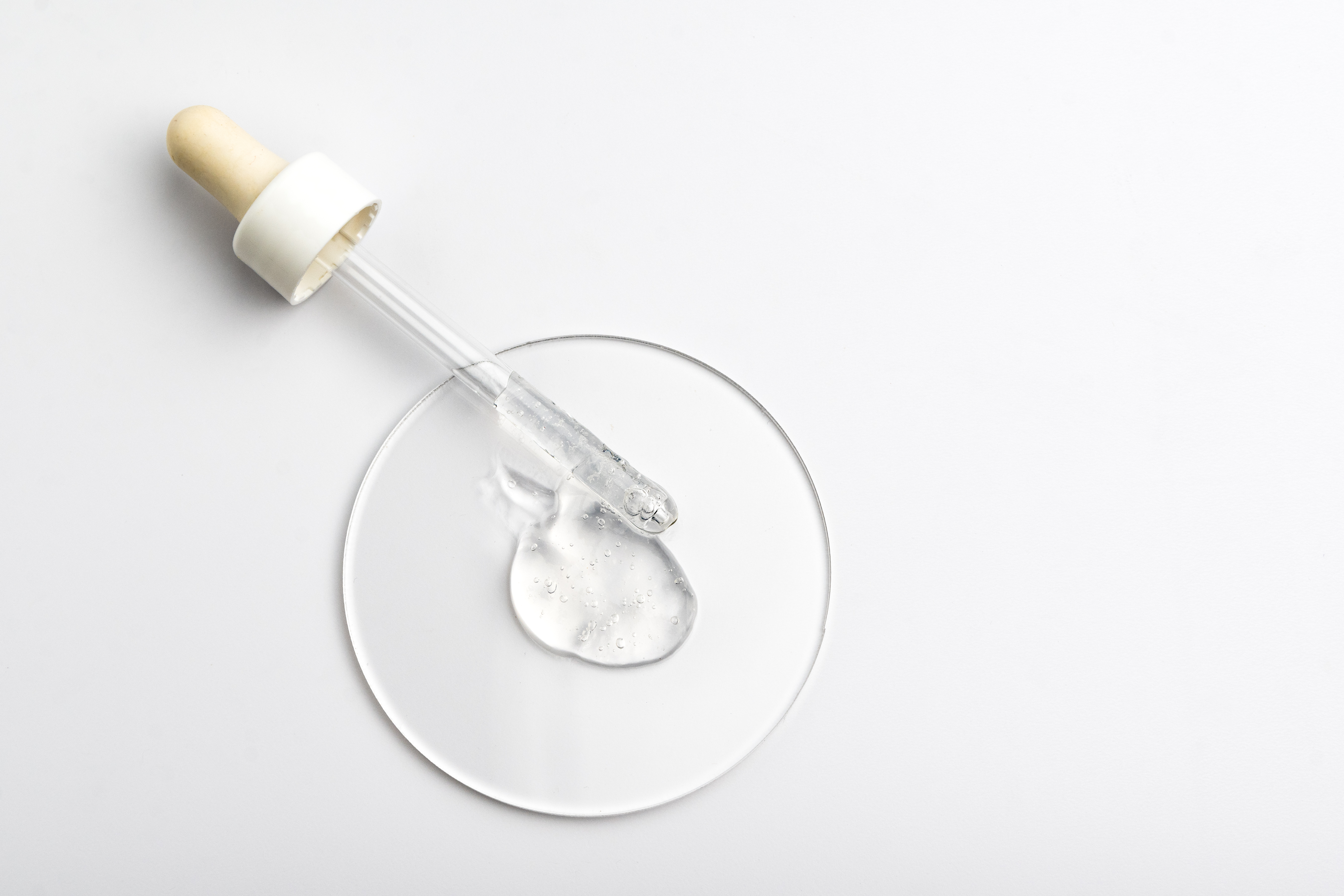 Une pipette en verre avec un liquide transparent visqueux se répandant sur un cercle de verre
