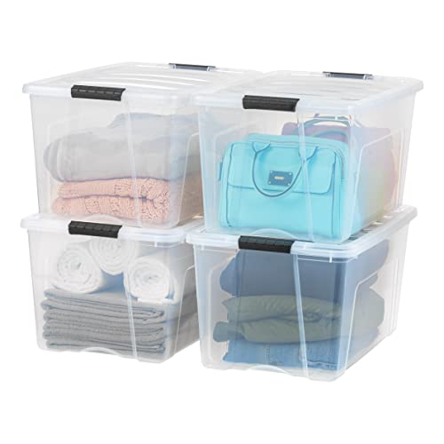 Clear 72 QT Colons de stockage en plastique empilables avec les couvercles. Quatre disposés deux par deux remplis de serviettes pliées, de vêtements et de sacs à main