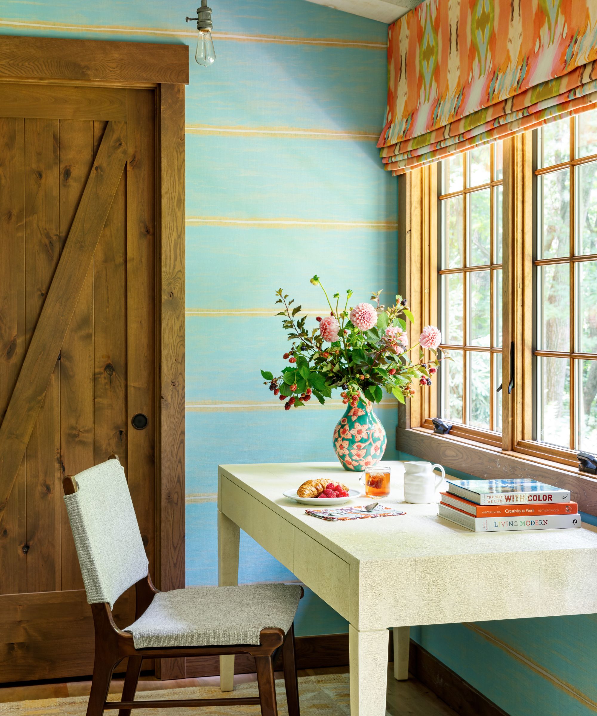 Bureau devant la fenêtre avec un mur rayé à motifs oranges à motifs orange et bleu et jaune