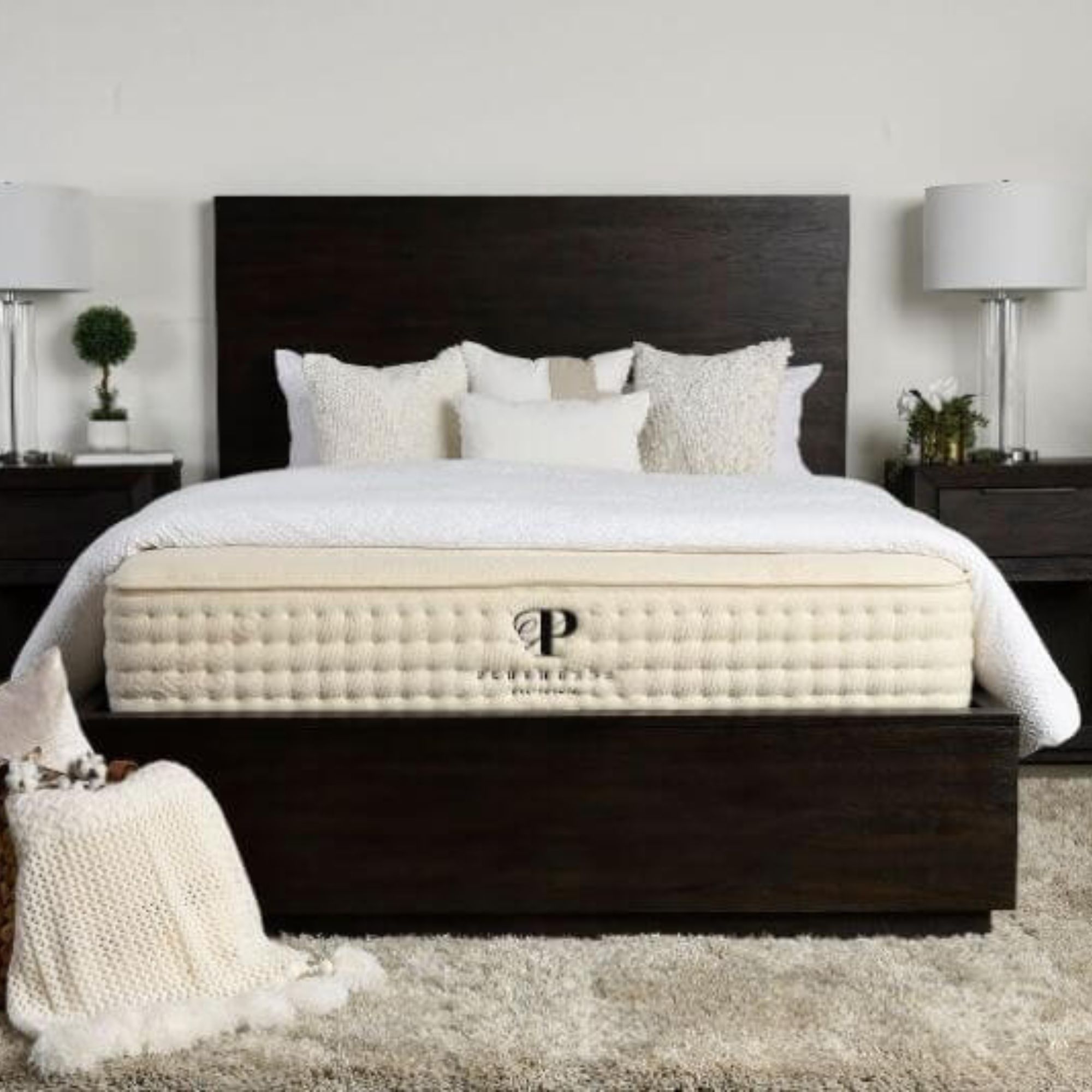 Un matelas en peluche sur un lit avec des oreillers contre un mur blanc.