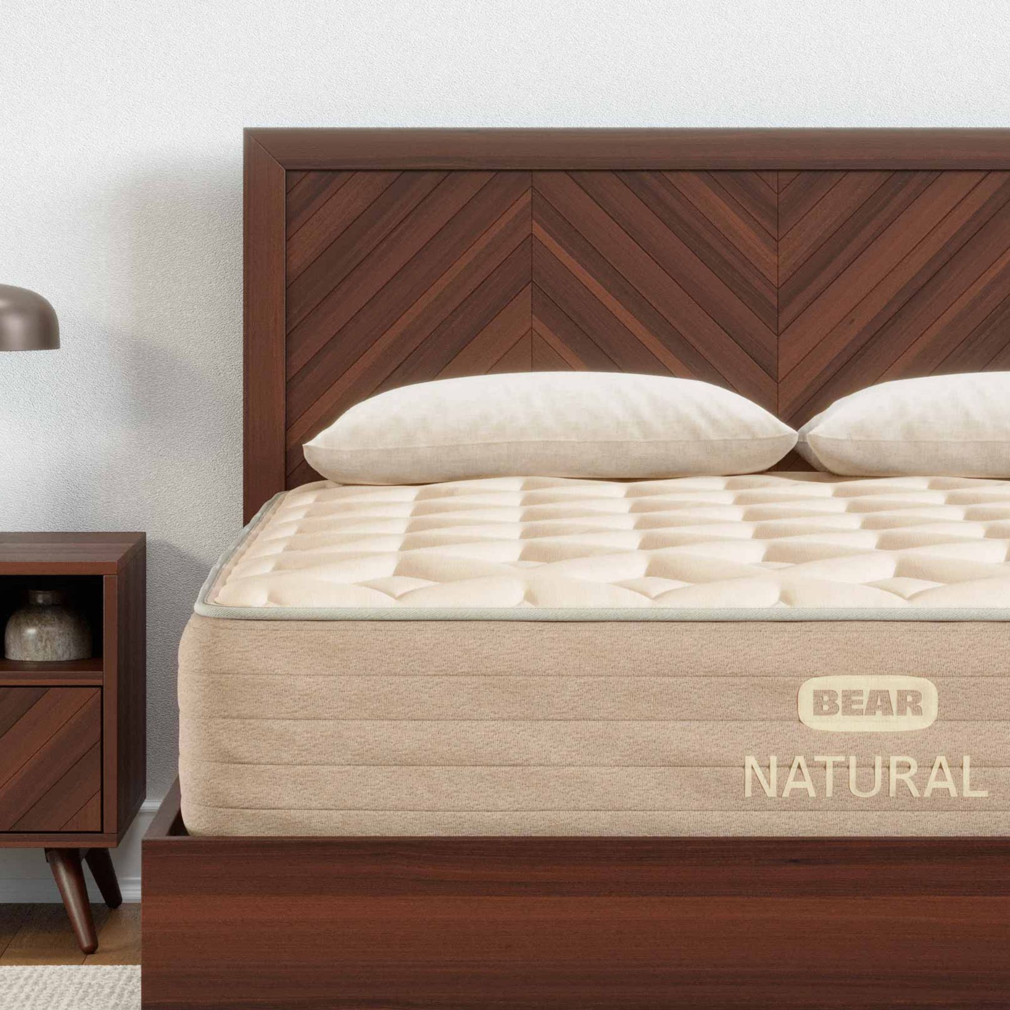 Le coin du matelas naturel Bear sur un cadre de lit en bois contre un mur blanc.