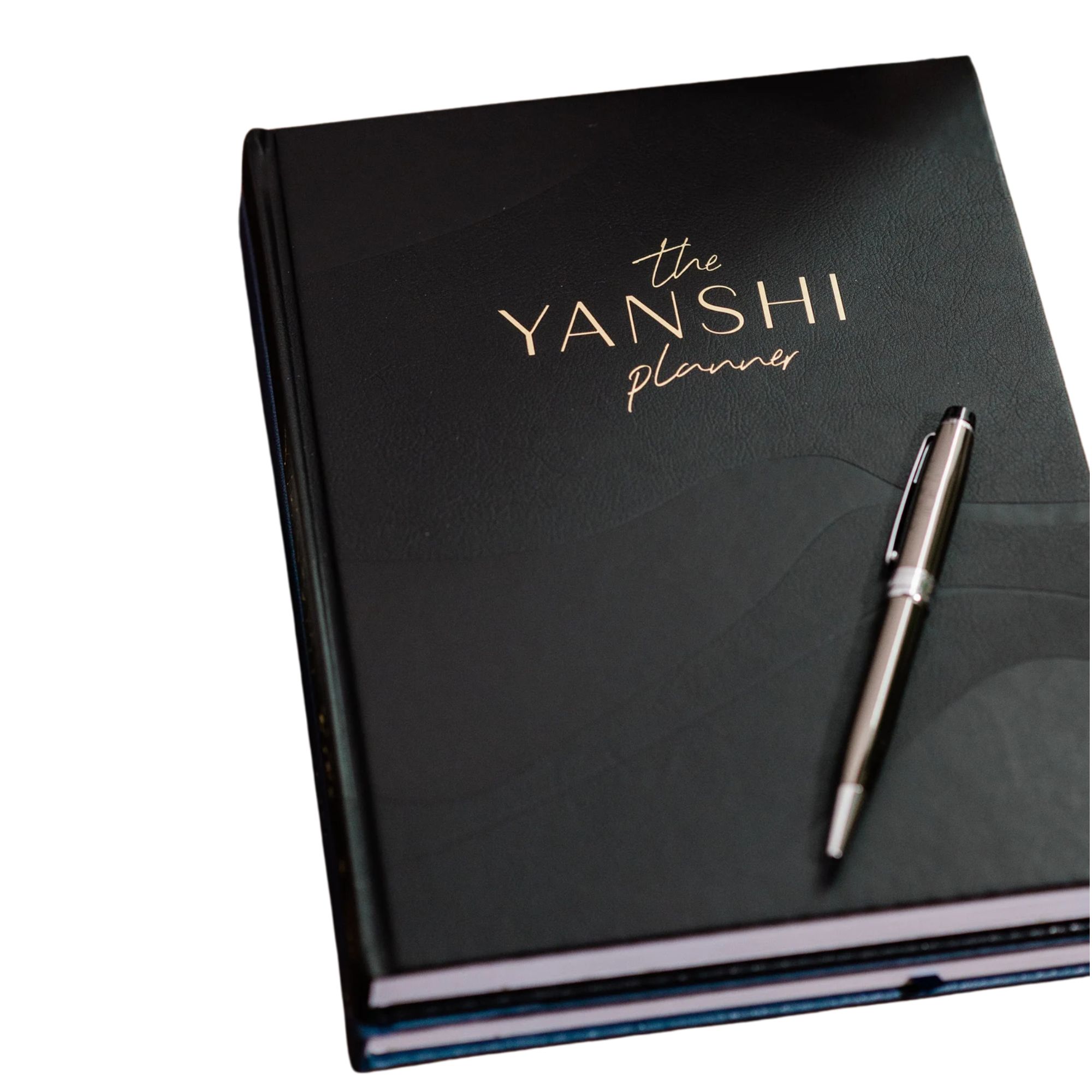 Un planificateur de budget noir avec du texte en or et un stylo noir et argenté reposant sur le dessus