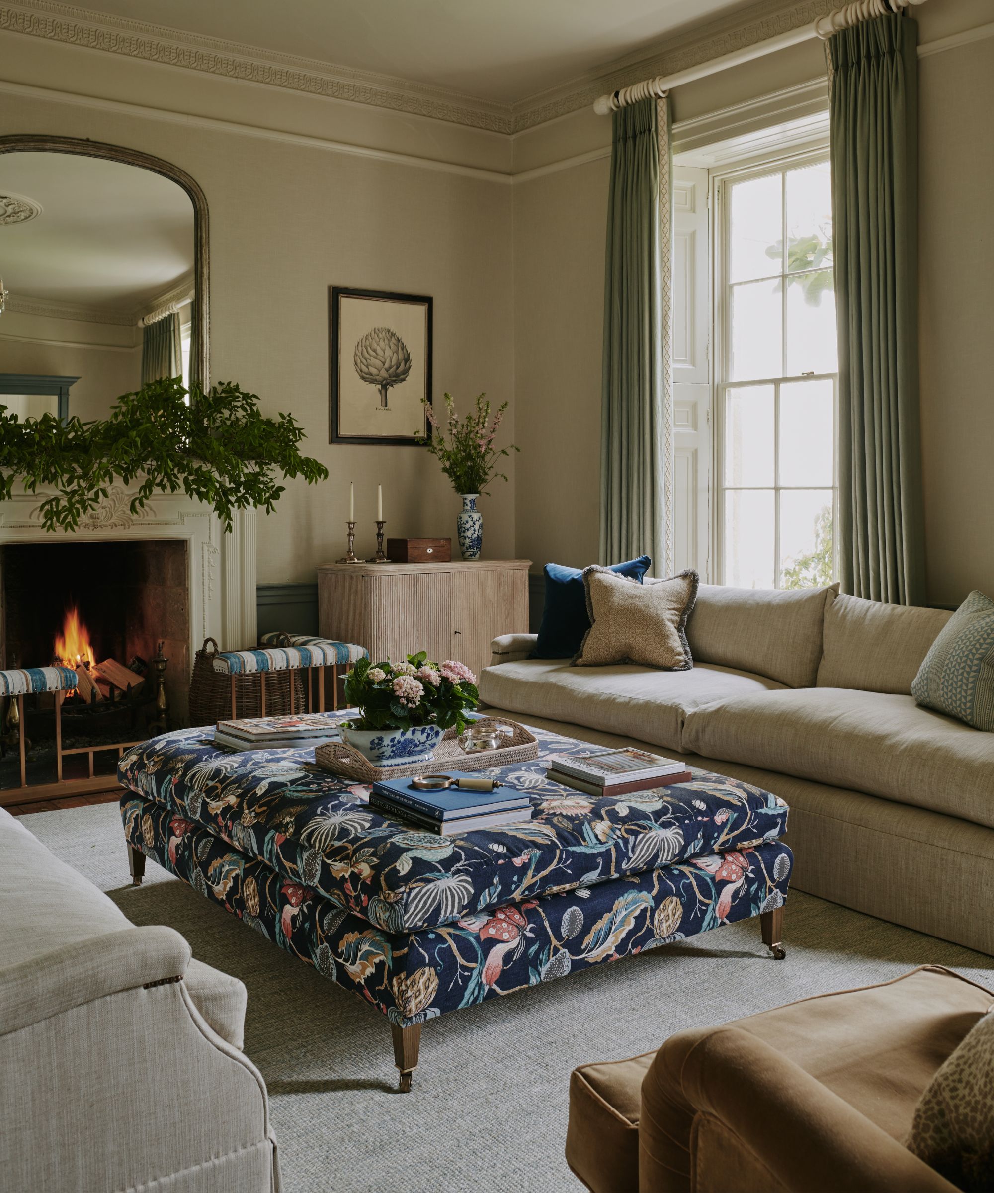 salon anglais neutre traditionnel avec une grande cheminée décorée de feuillage et un grand pouf à motifs de la Marine