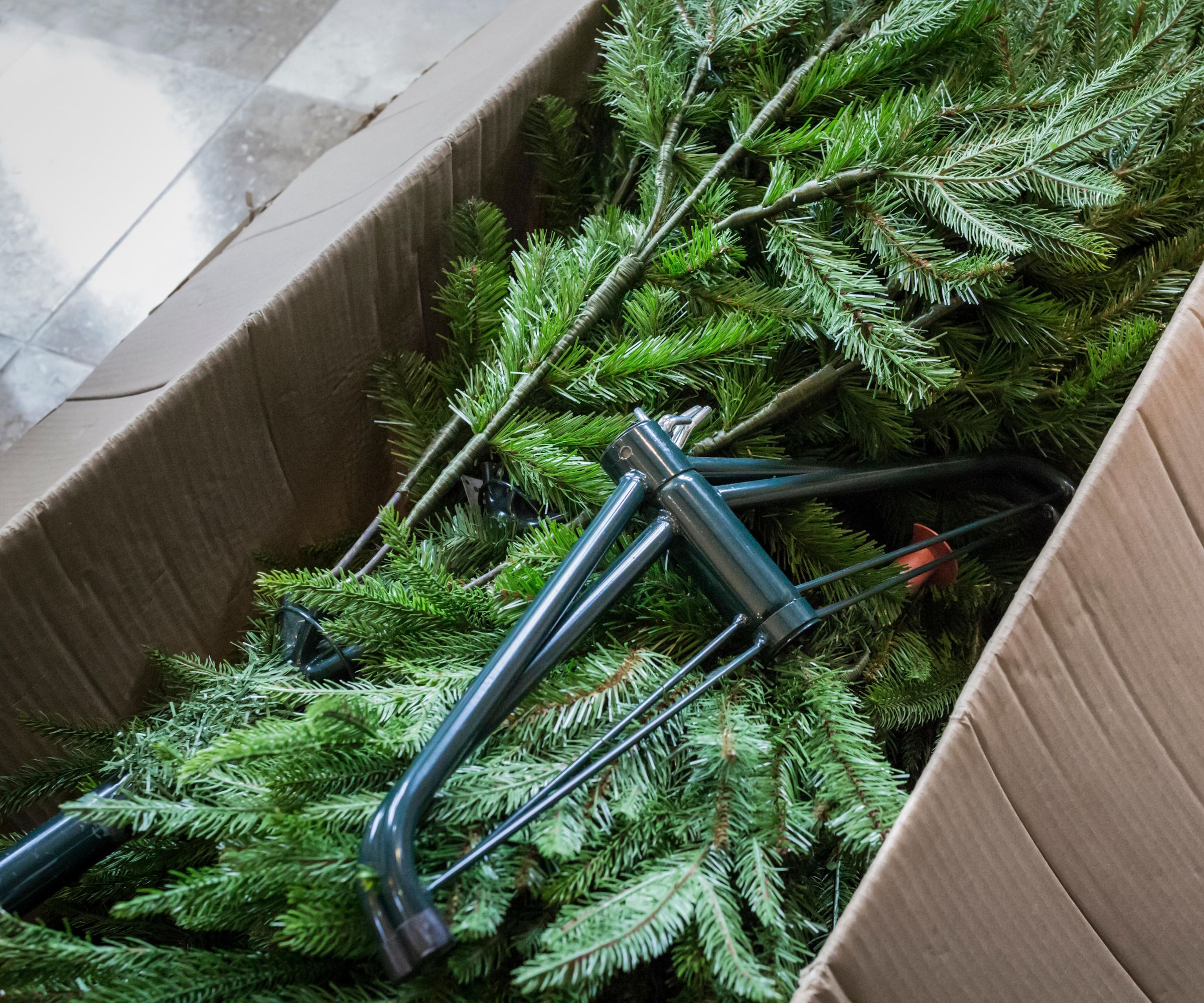 Un faux arbre de Noël plié dans une boîte de rangement