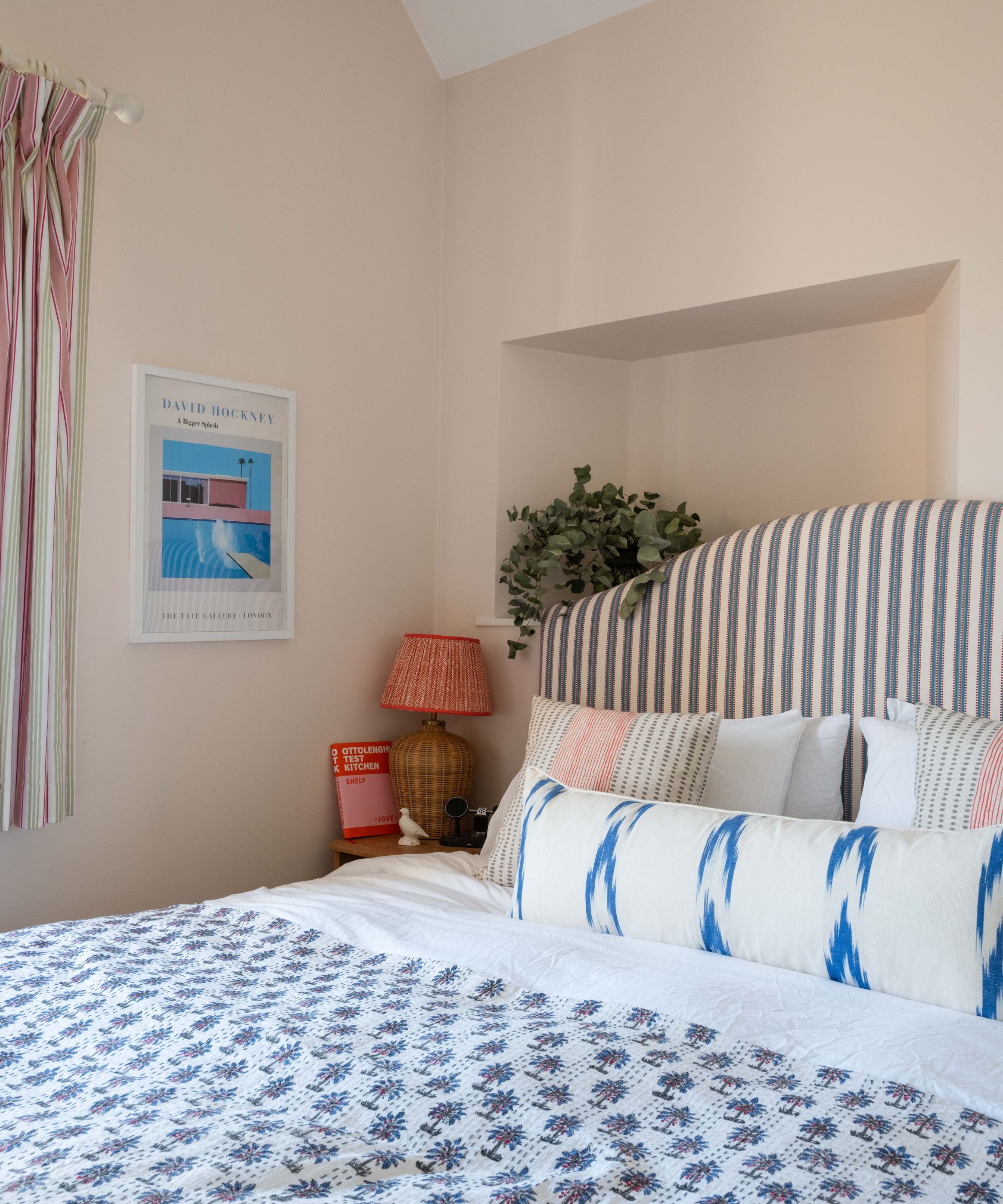 coin de la chambre avec des murs rose pâle et une literie à motifs bleus et une tête de lit rayée