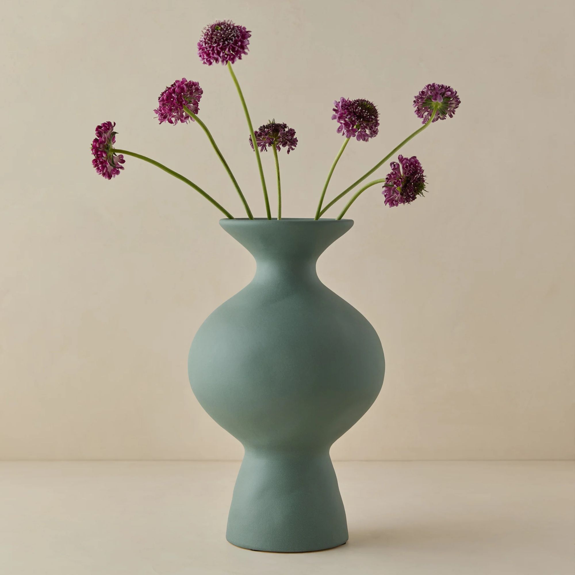 Vase sculptural sarcelle avec des fleurs violettes