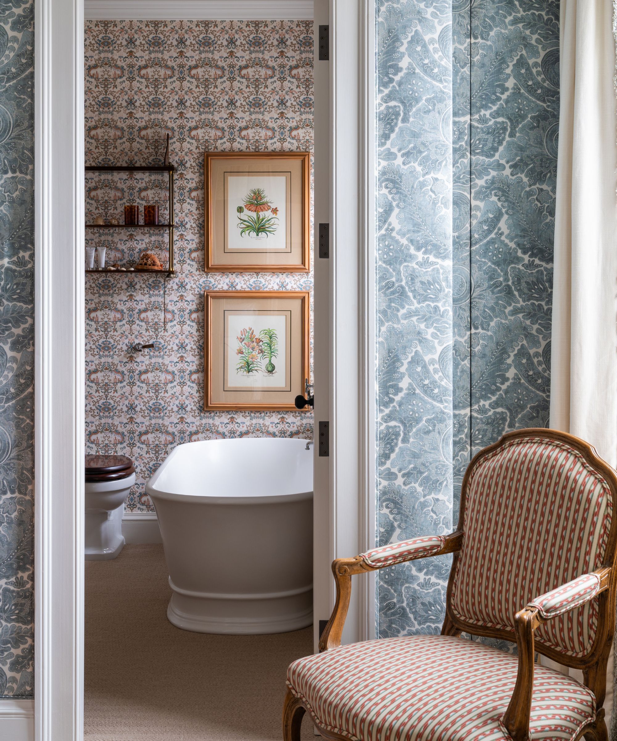 Salle de bain en papier peint avec imprimés de fleurs vintage, baignoire et étagère et chaise garnie vintage