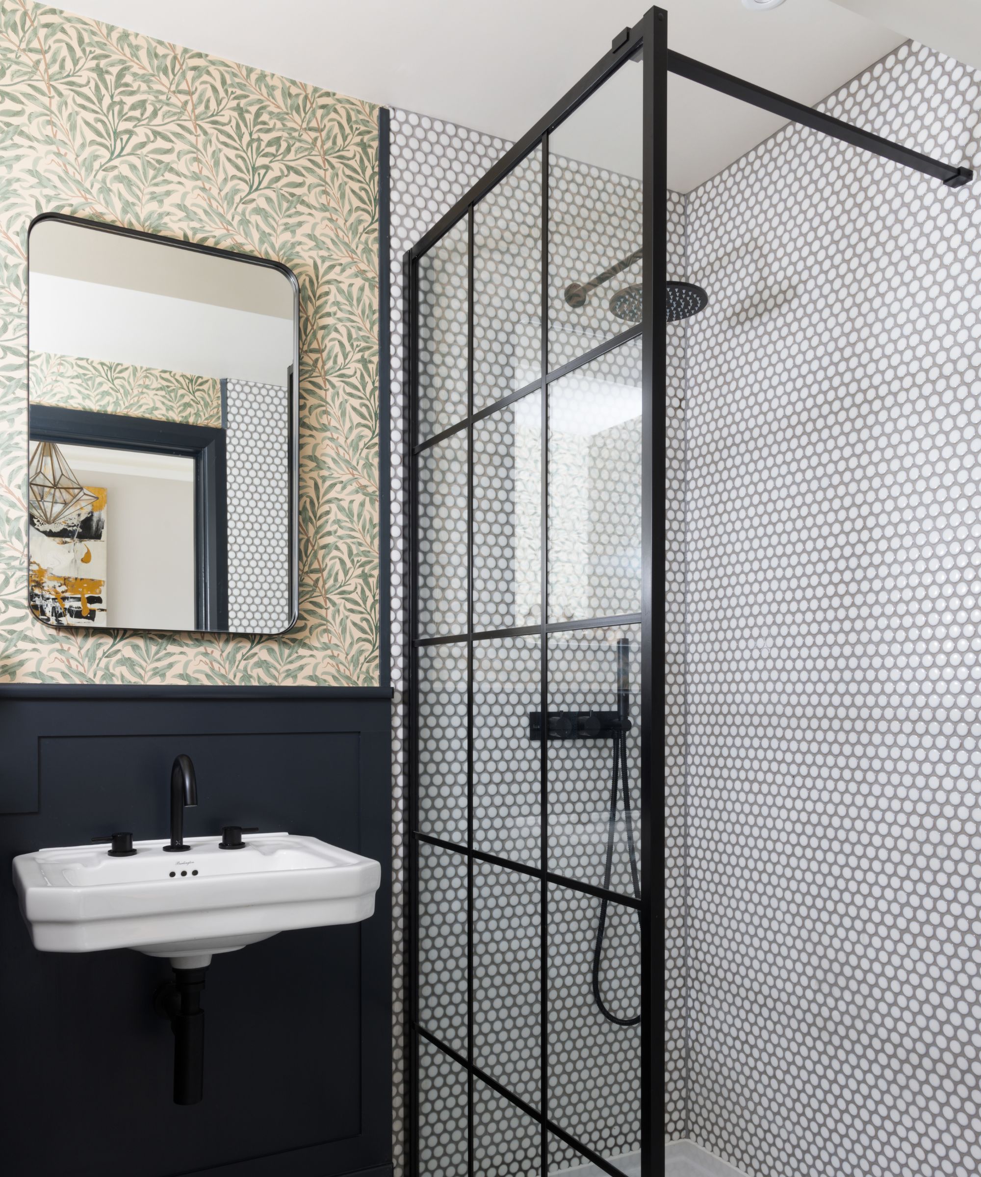 Une petite salle de bain avec fond d'écran botanique et un écran de douche en verre à ossature noire