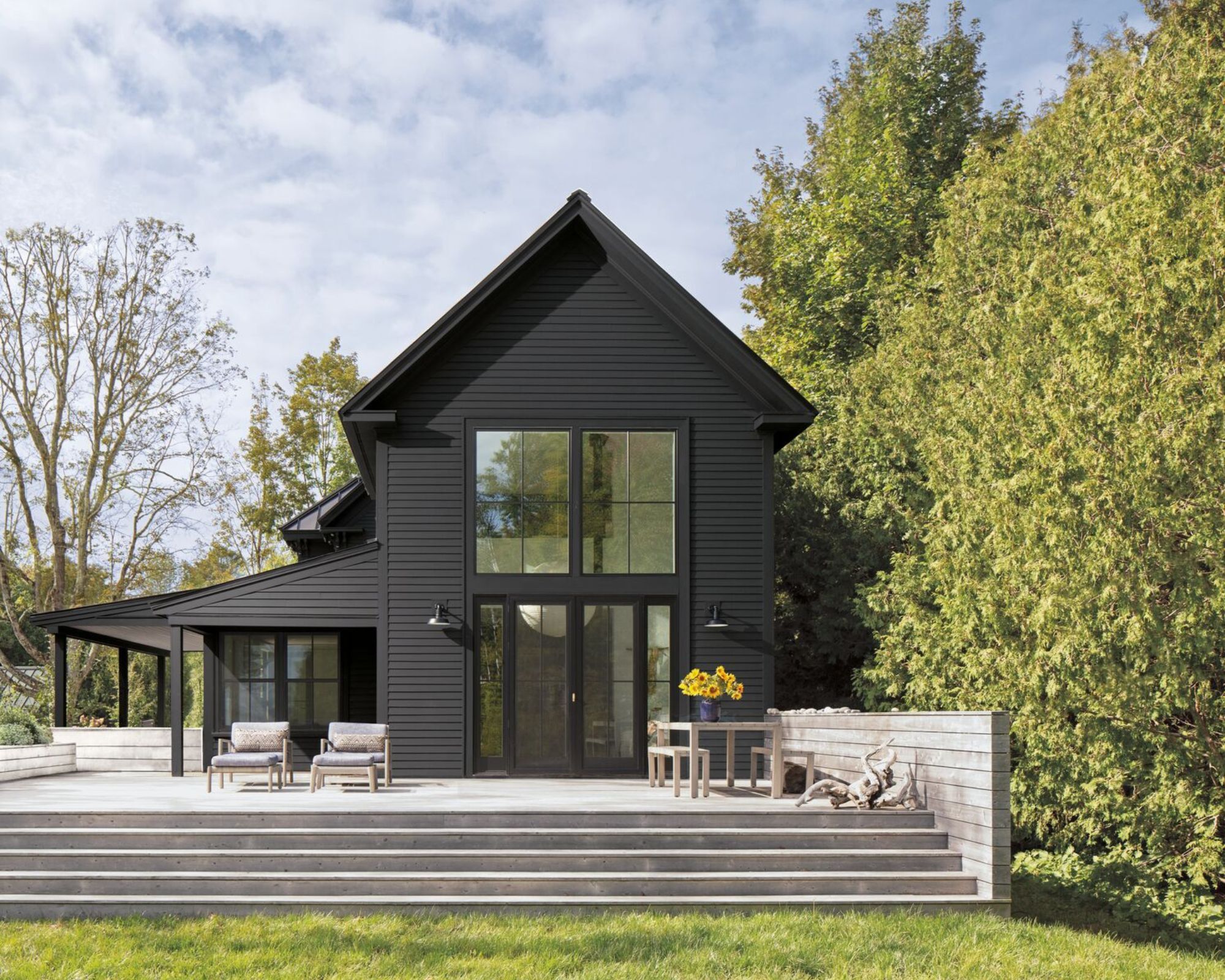 L'extérieur d'une maison moderne avec un platelage environnant. Étapes de la terrasse vers une zone législative. La maison est peinte en peinture noire.
