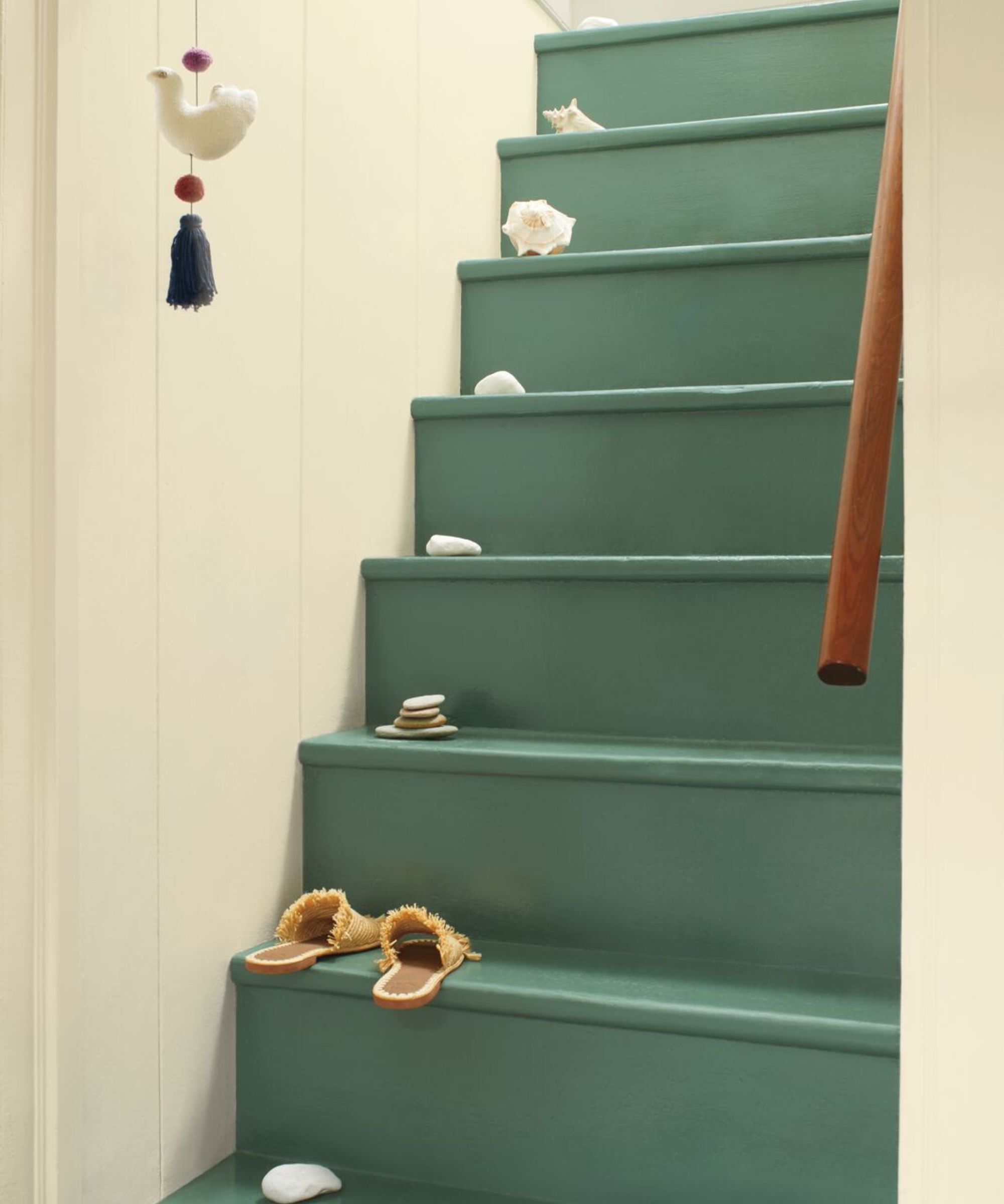 Escaliers peints dans une peinture verte fraîche. Il y a quelques petits articles à chaque étape, y compris les sandales et les galets.
