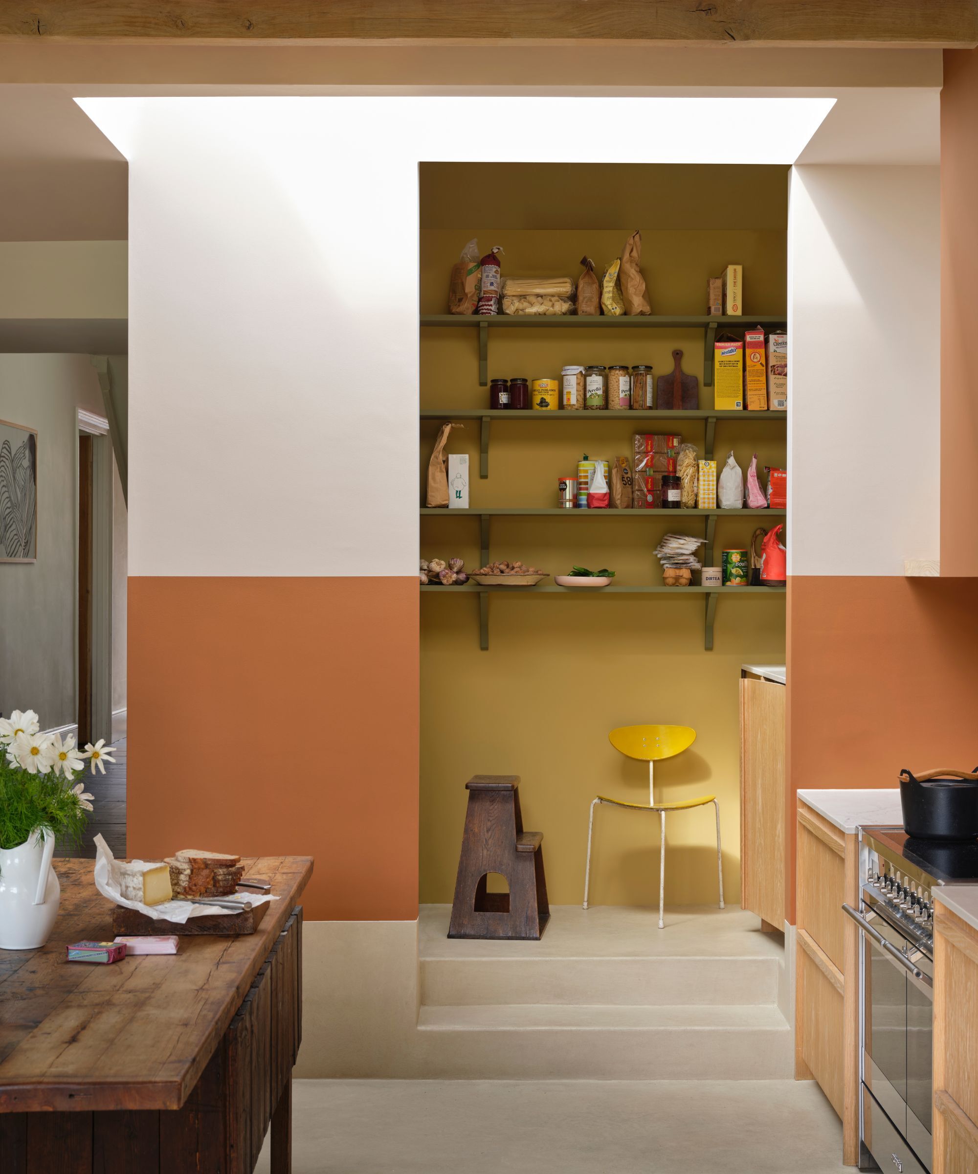 Une cuisine menant à un garde-manger, les murs du garde-manger ont été peints dans un jaune pastel